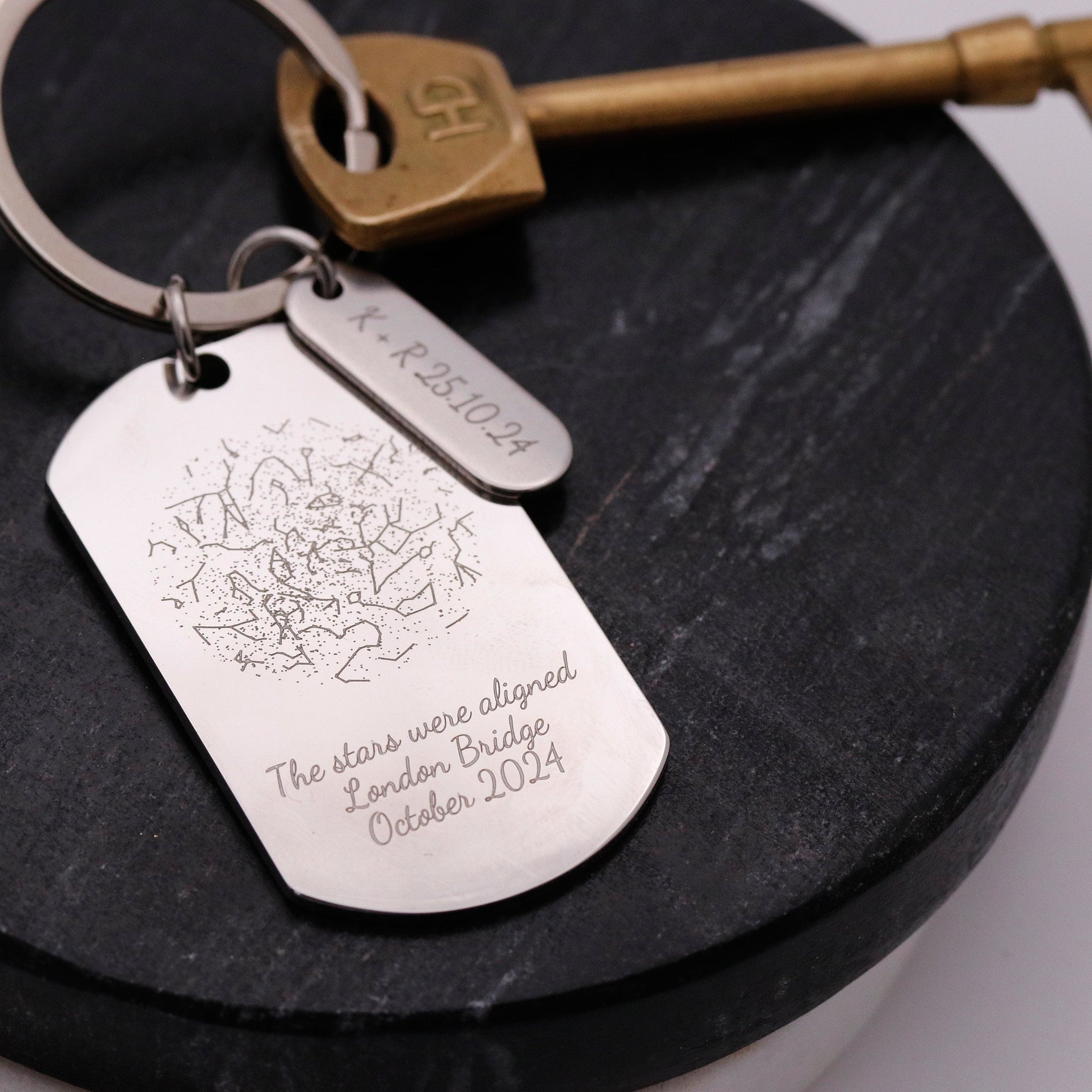 Silver dog tag keychain with engraved text on a dark surface