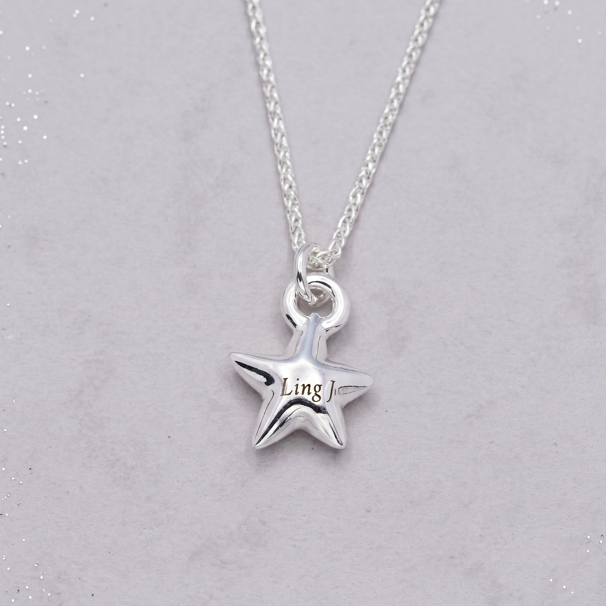 Silver star-shaped pendant necklace on a light gray background