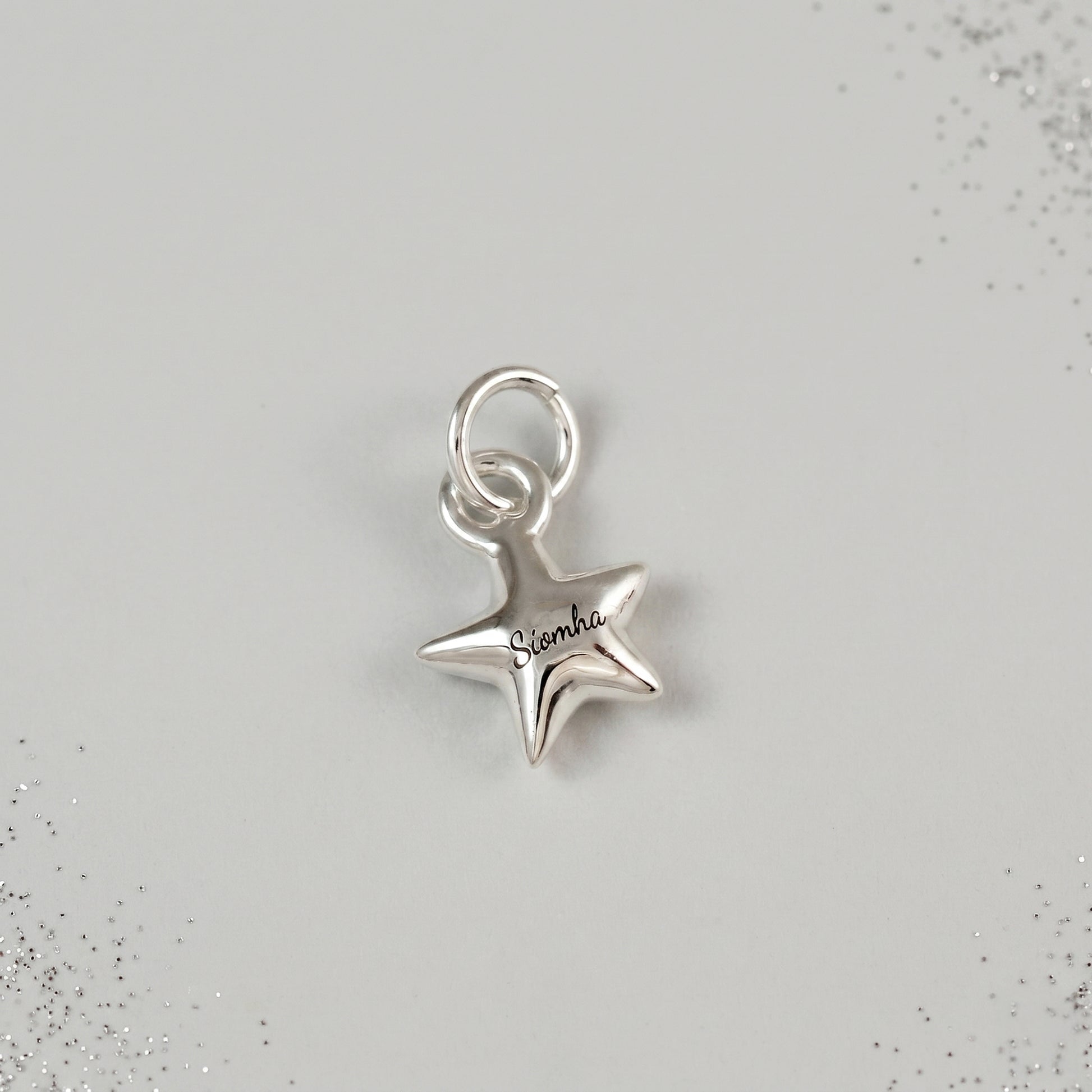 Silver star-shaped charm with 'Sienna' engraving on a light gray background
