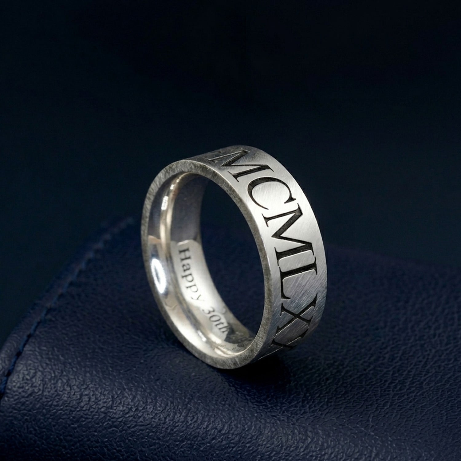 Silver ring with Roman numerals on a dark blue fabric background