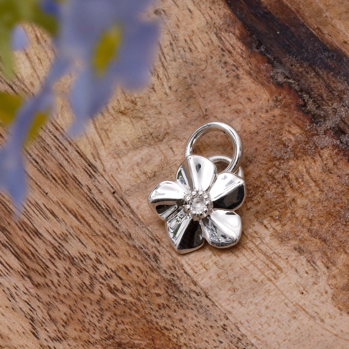 Silver flower-shaped pendant on a wooden surface