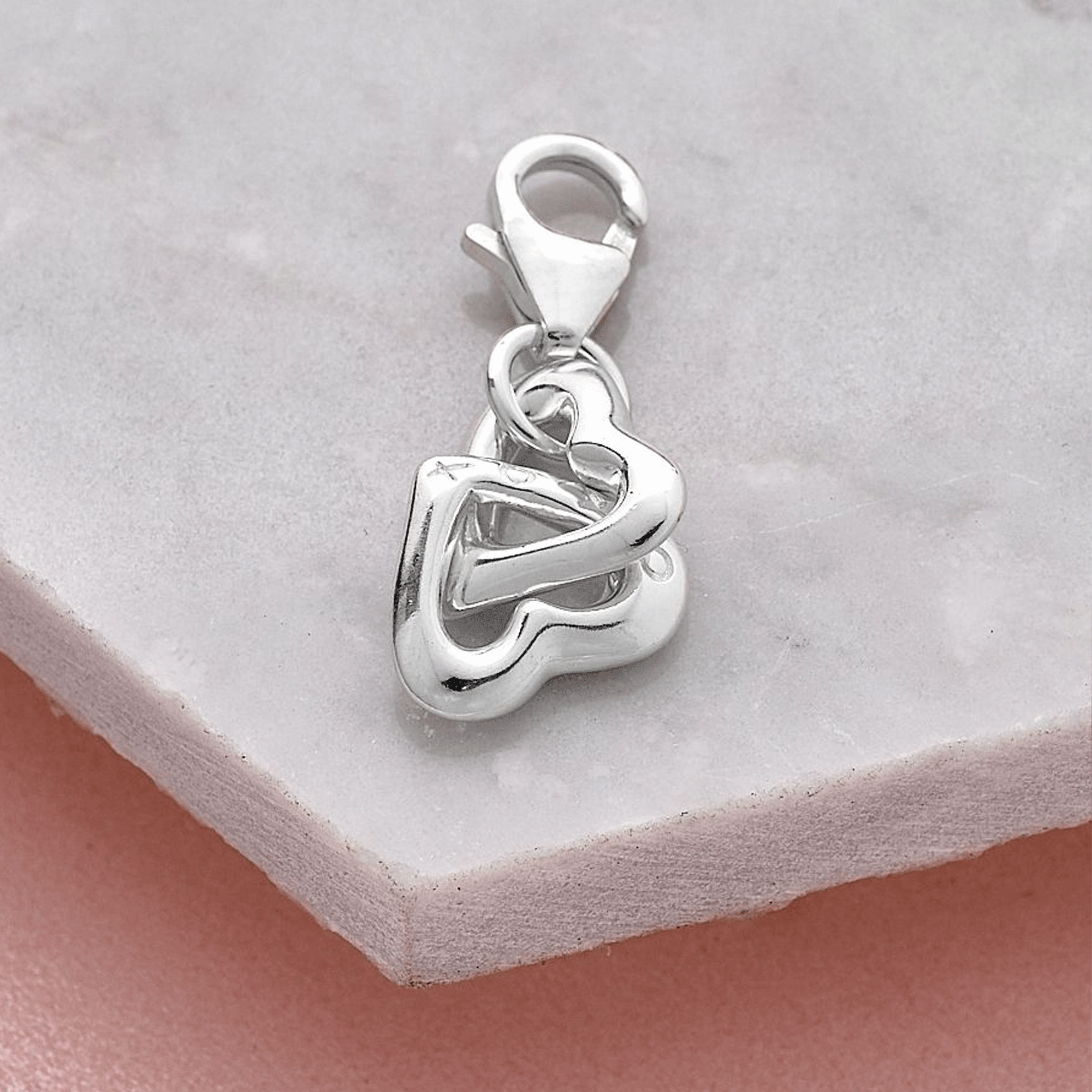 Silver twin heart-shaped pendant on a light gray background