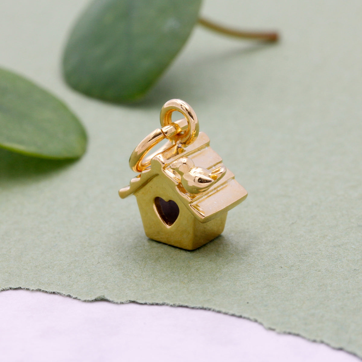 Gold-plated bird house charm with tiny bird perched on roof and heart entrance