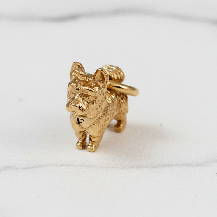 Gold dog-shaped charm on a light background