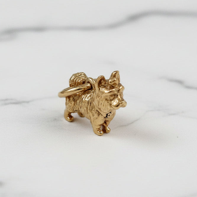 Gold dog-shaped charm on a speckled white surface