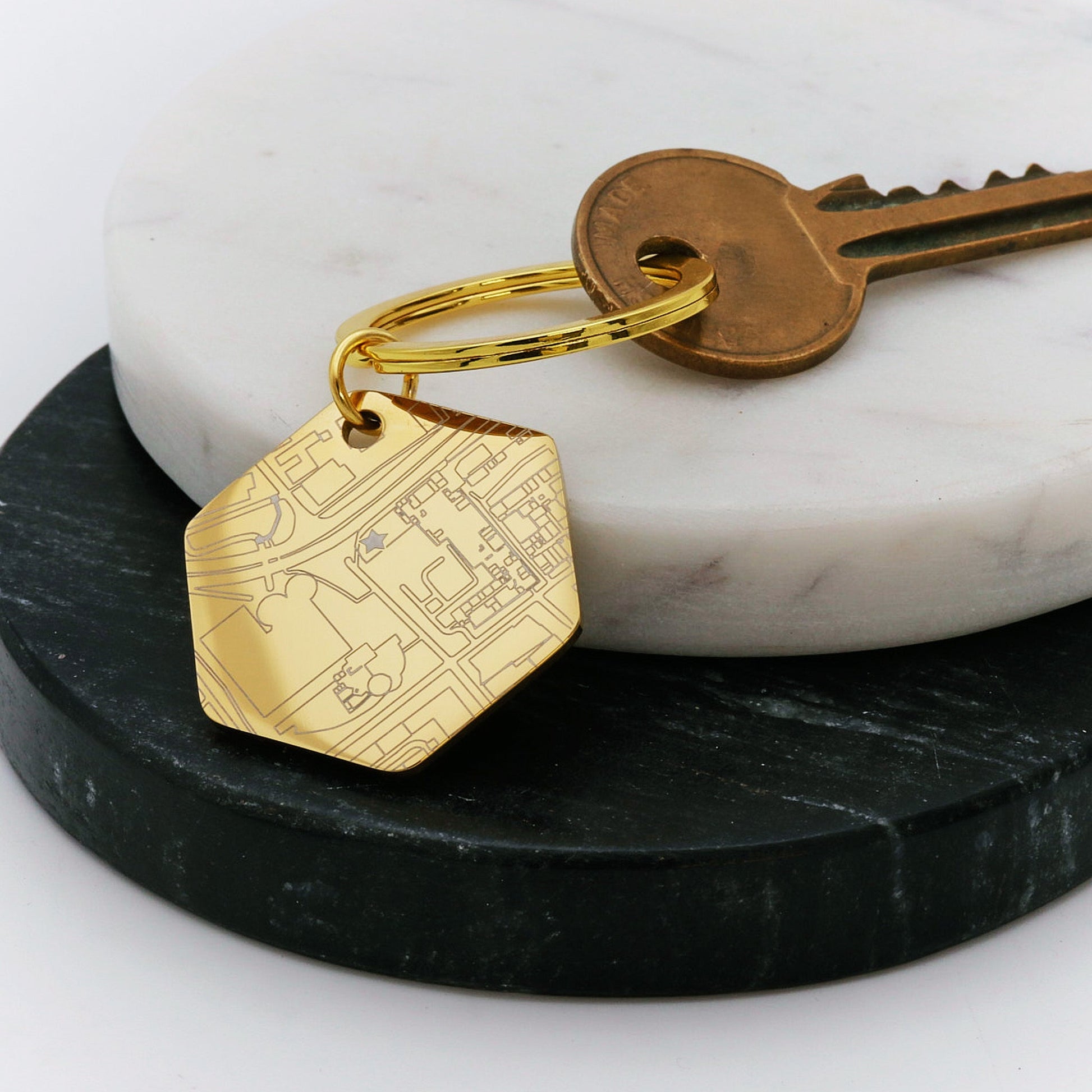 Gold keychain with street map design on a marble surface