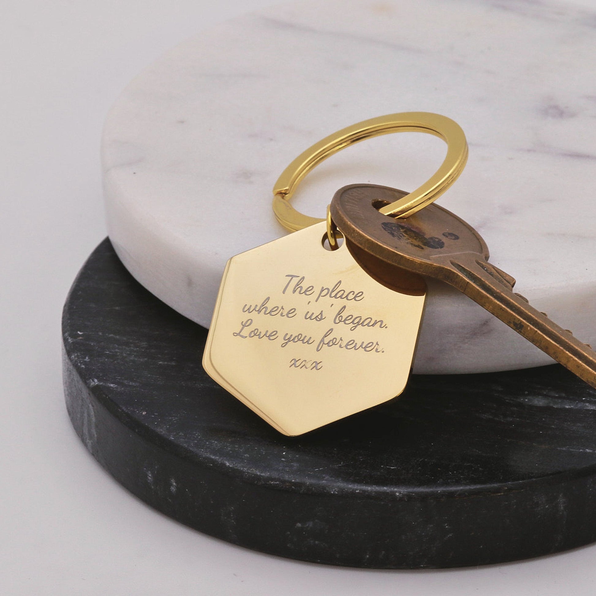 Gold keychain with engraved message on a marble surface