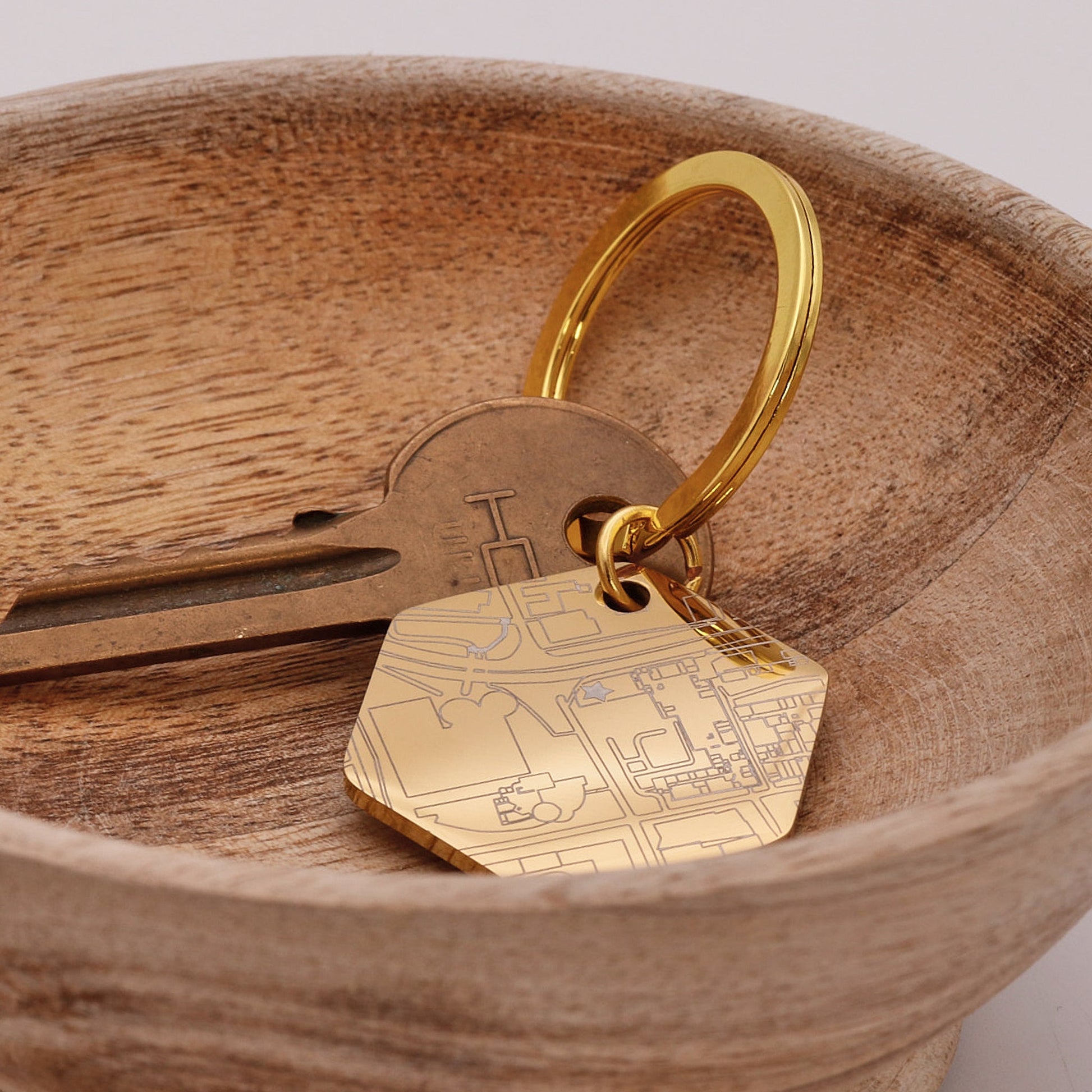 Gold keychain with a street map design on a wooden surface