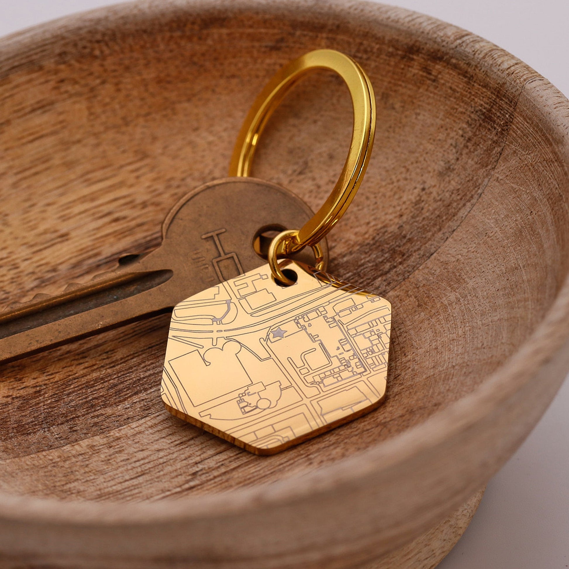 Gold keychain with custom street map design on a wooden surface
