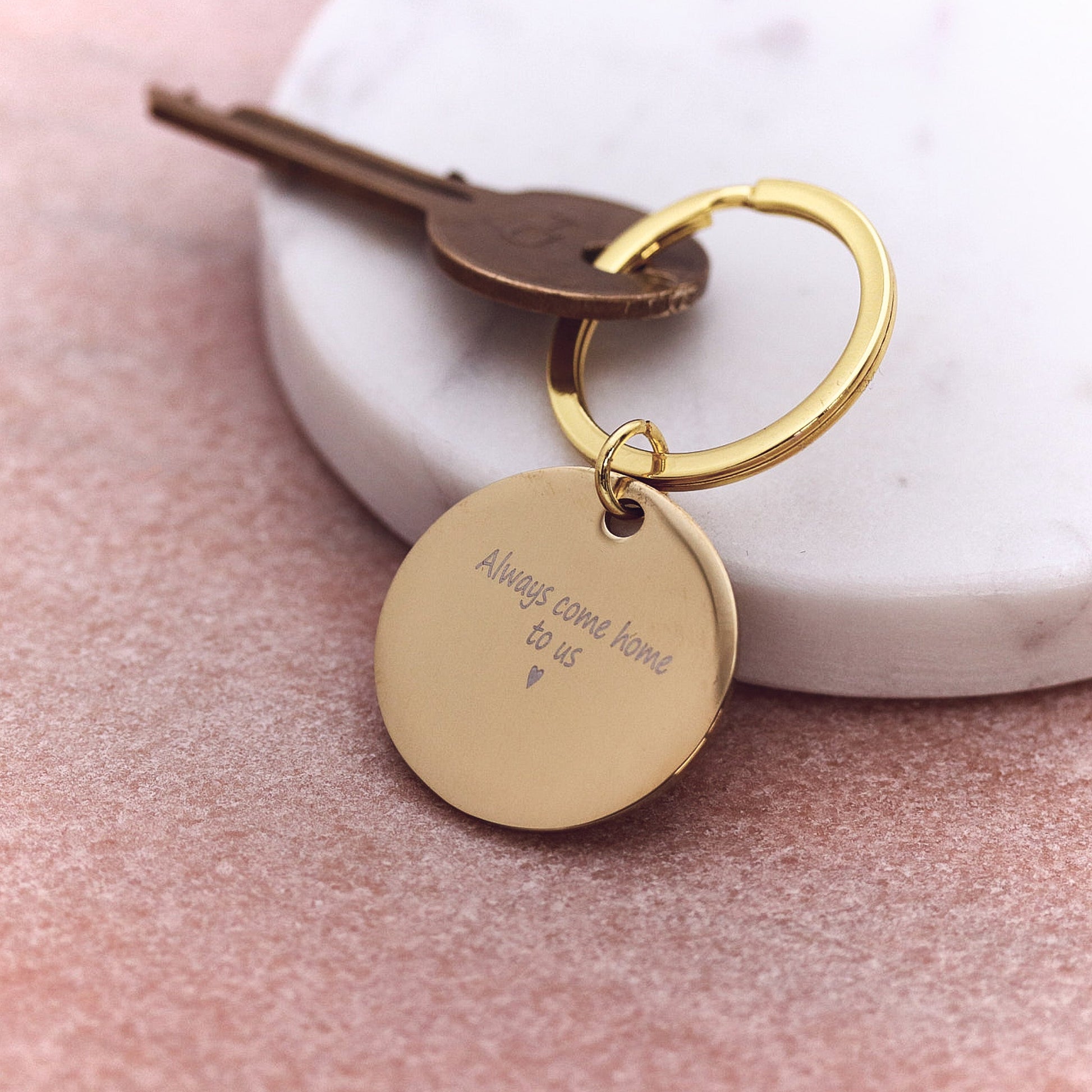 Gold keychain with engraved message on a marble surface