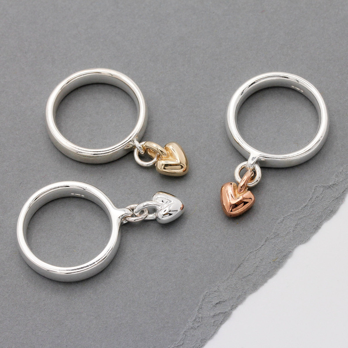 silver charm ring with dangling heart in silver, rose and gold hearts