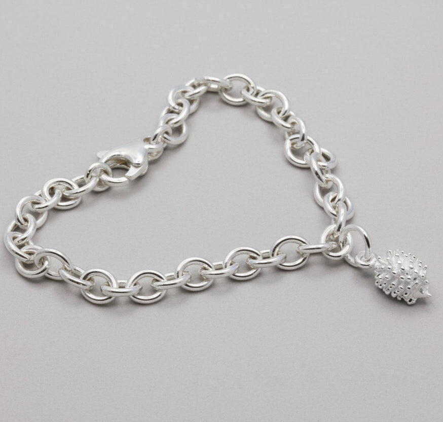 Silver chain bracelet with a hedgehog charm on a gray surface