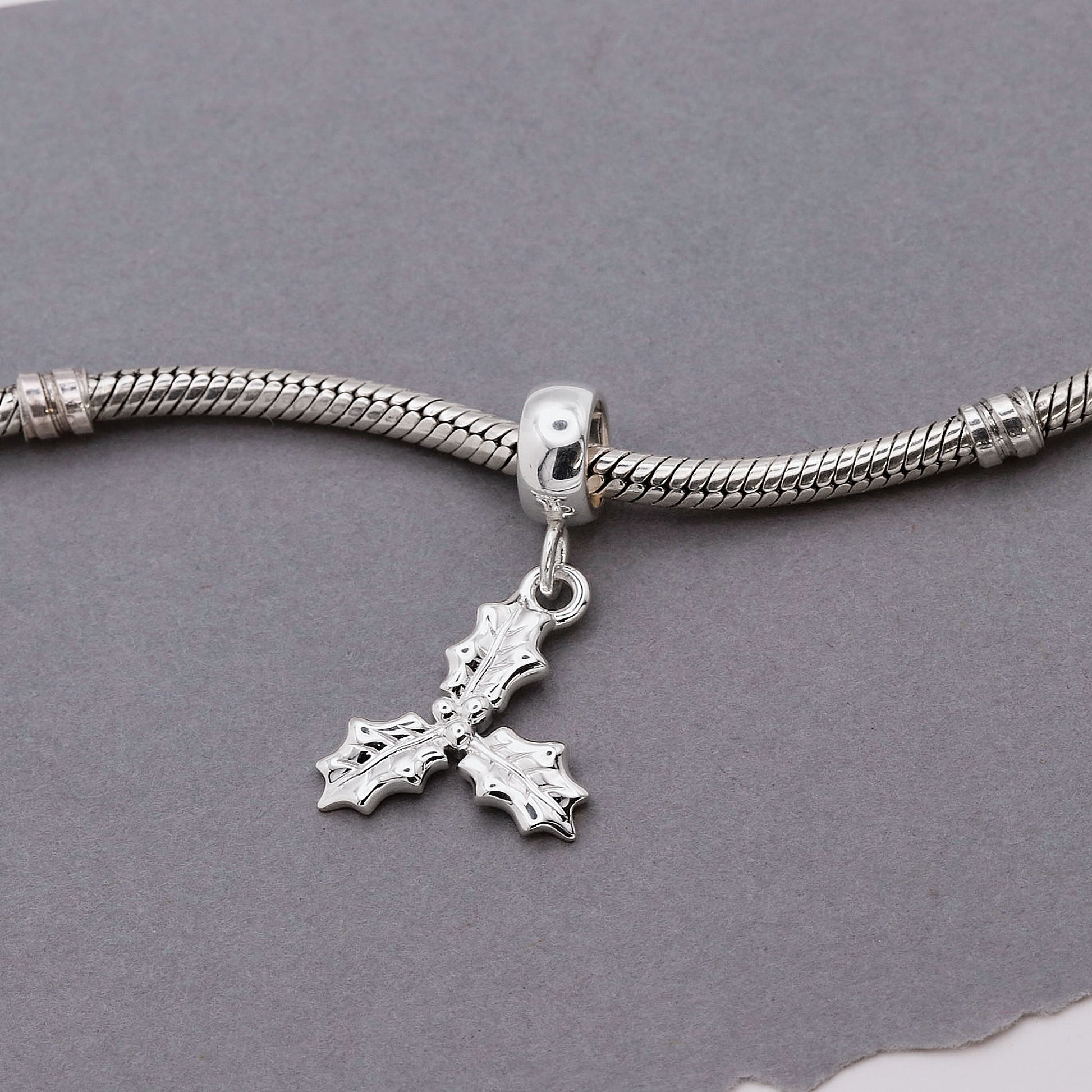 Silver bracelet with a cross charm on a gray background
