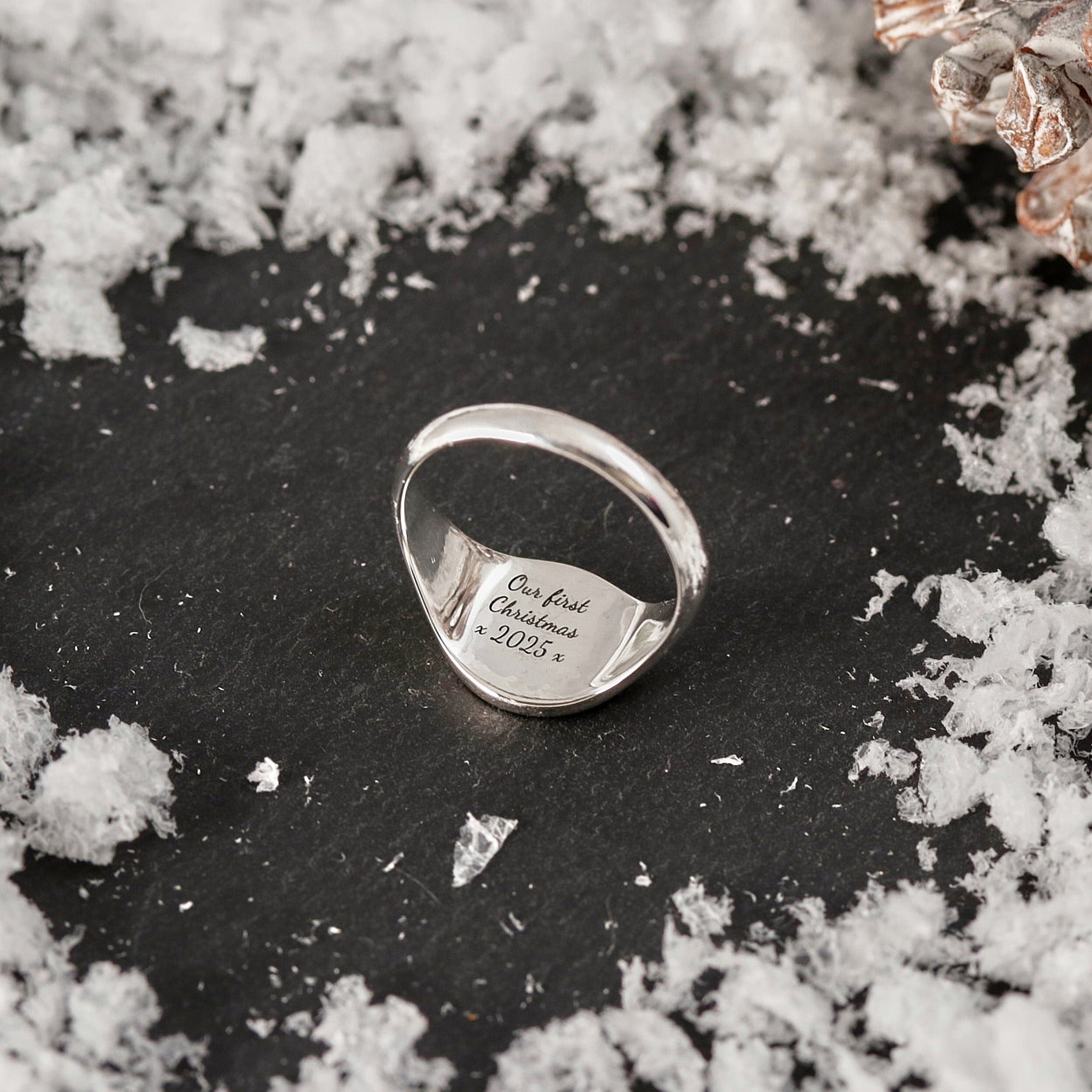 inside signet ring engraved with christmas 2023 on grey background with snow