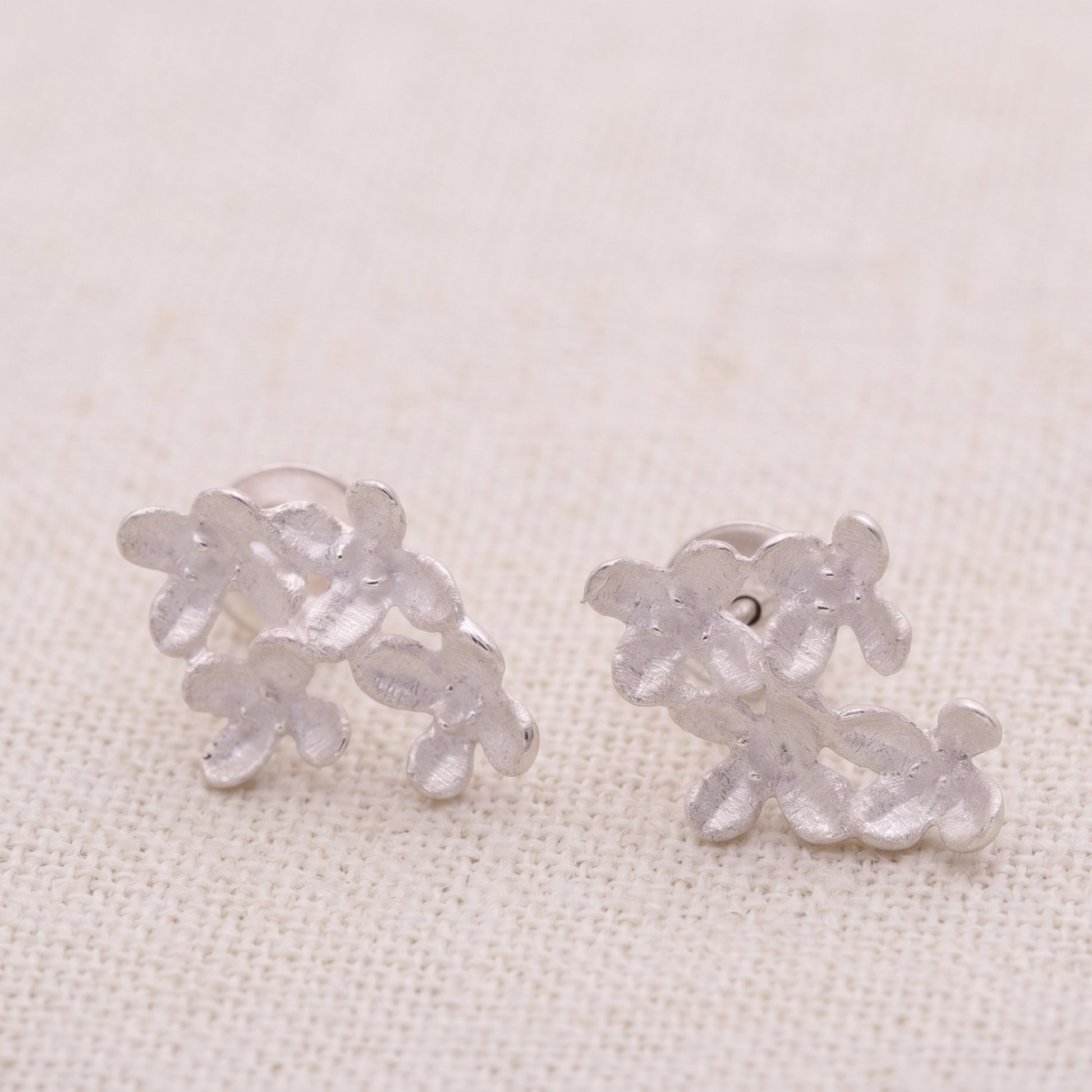 Pair of silver floral earrings on a light beige background