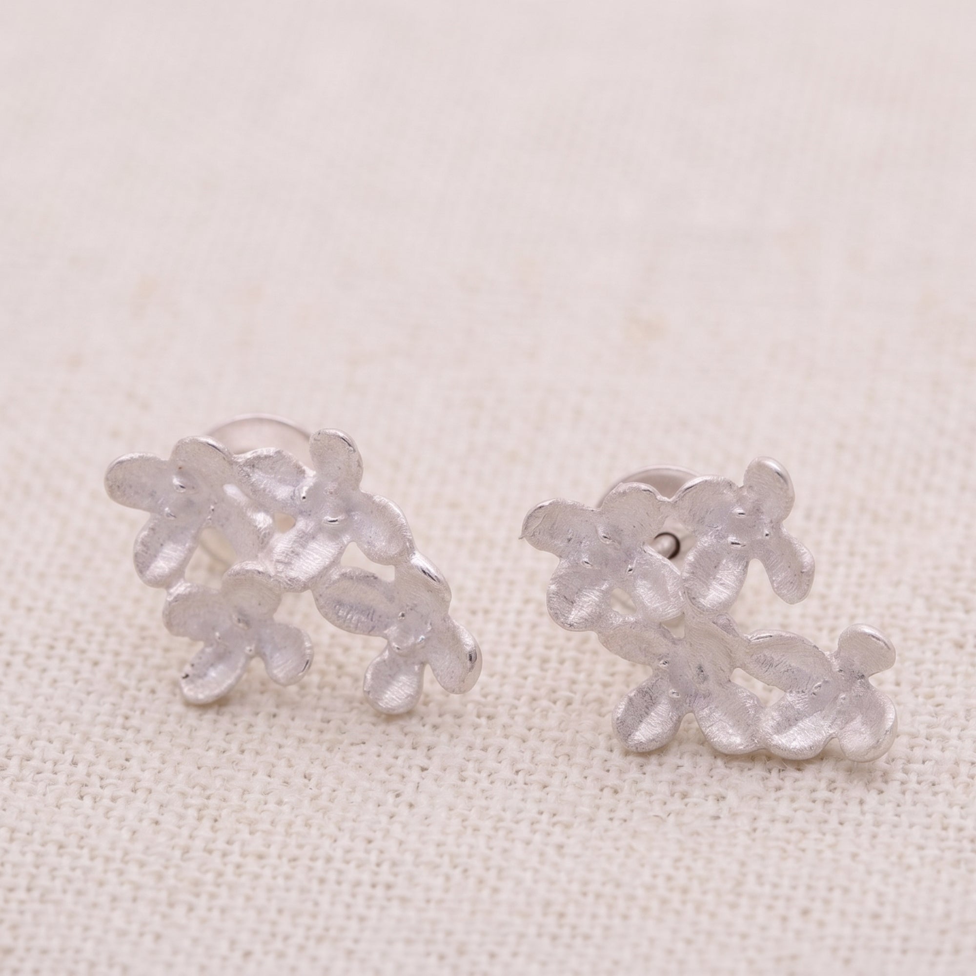 Pair of silver floral earrings on a light beige background