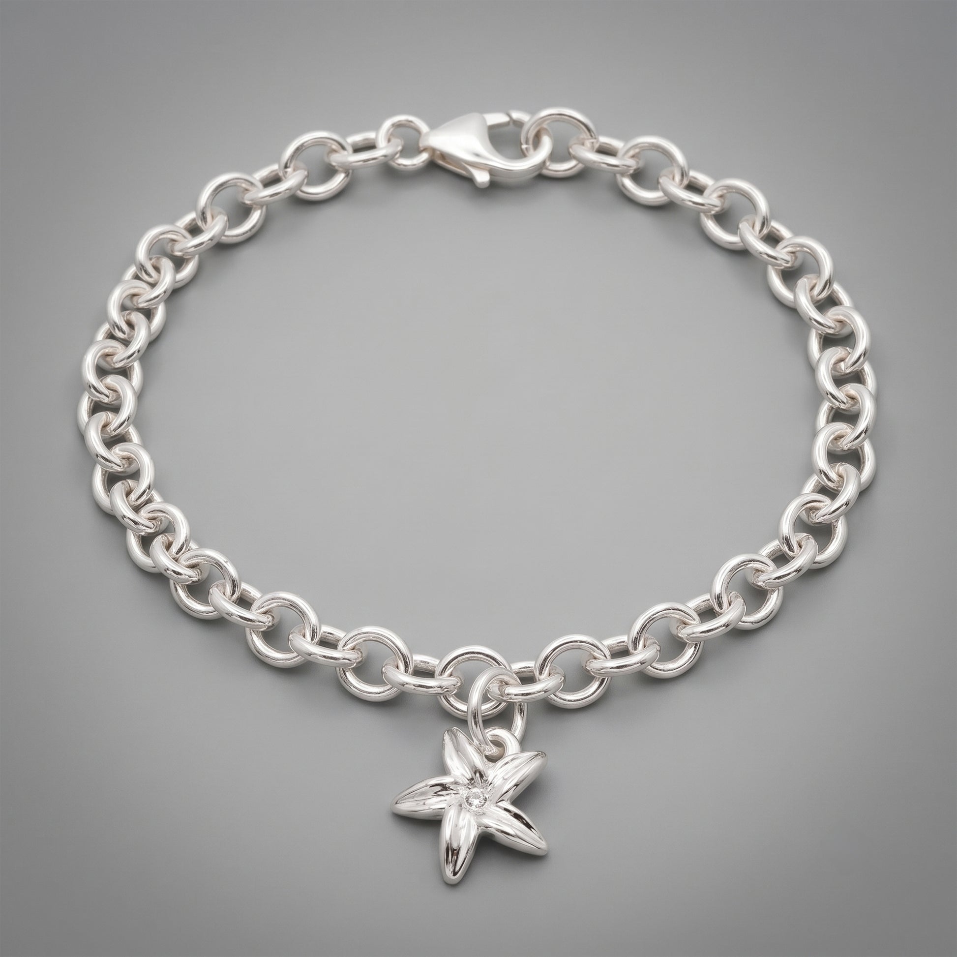 Silver chain bracelet with a flower-shaped charm on a gray background