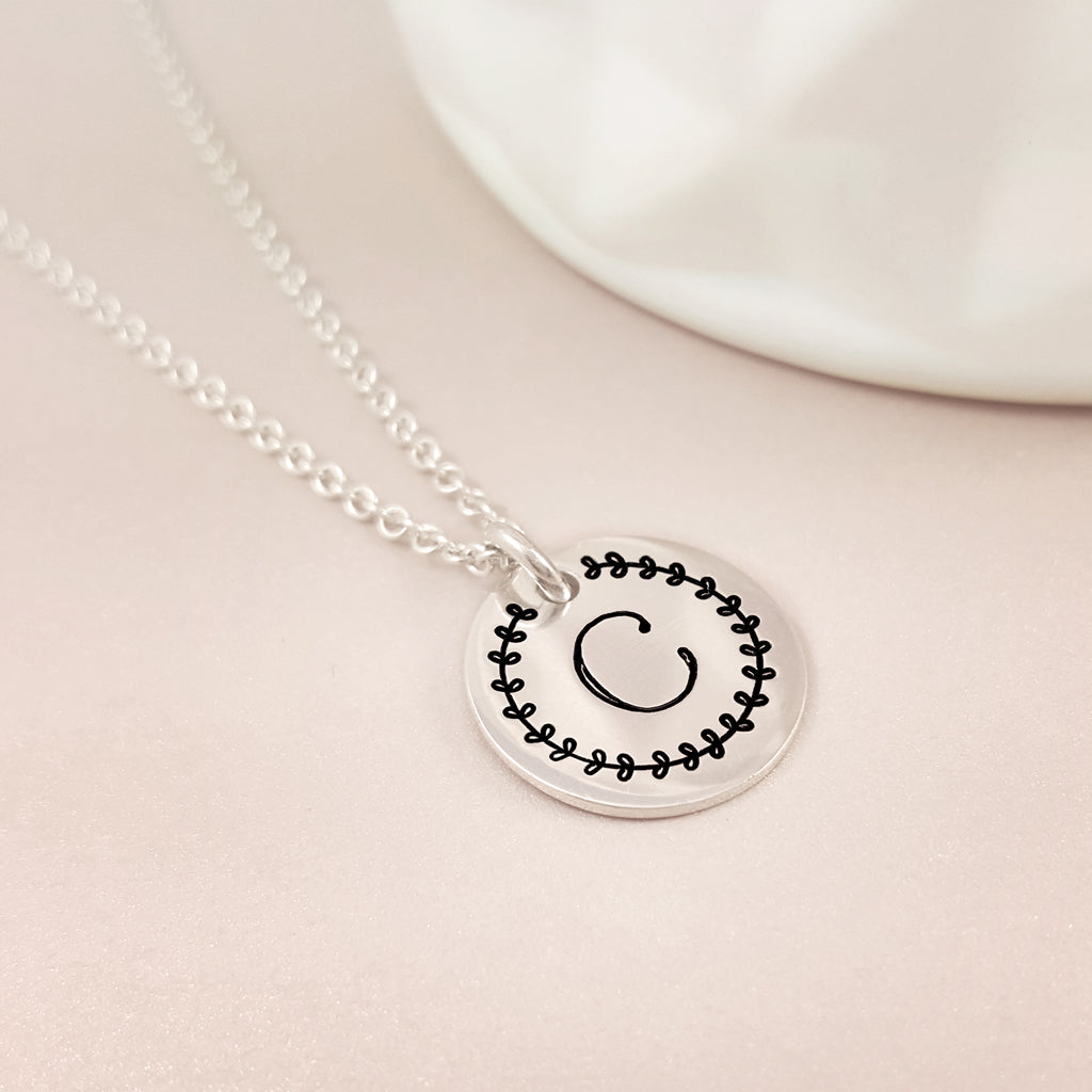 initial silver disc necklace with leaf border design