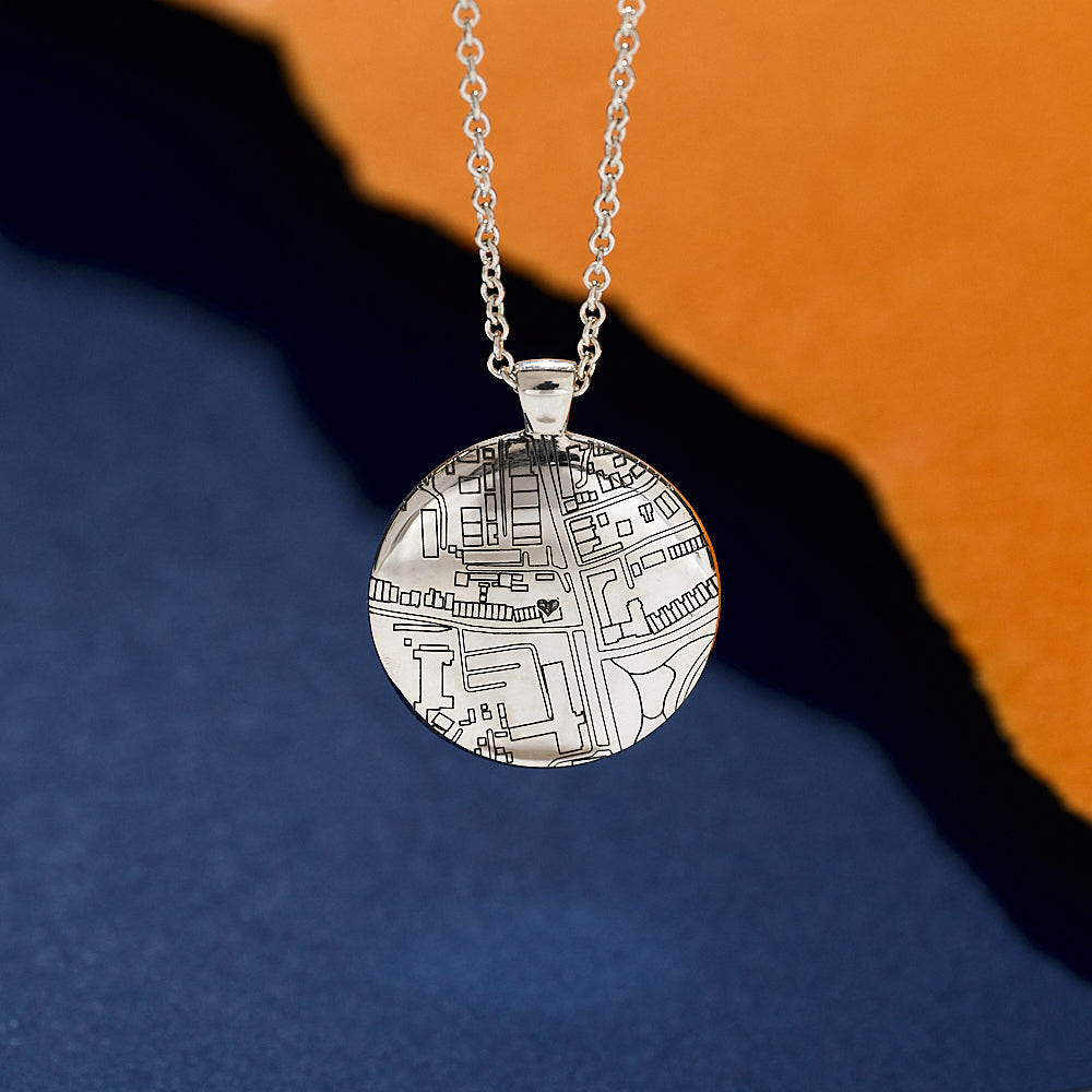 Silver necklace with a circular pendant custom street map design on a blue and orange gradient background