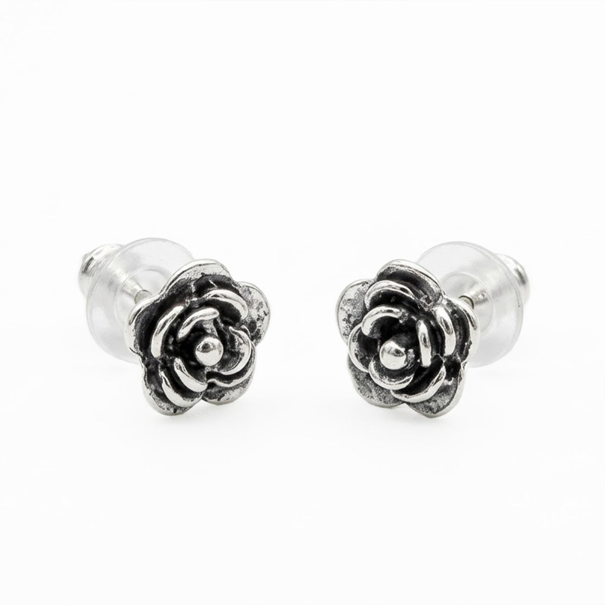 A pair of silver rose stud earrings with textured petals and clear glass backs, shown on a plain white background.