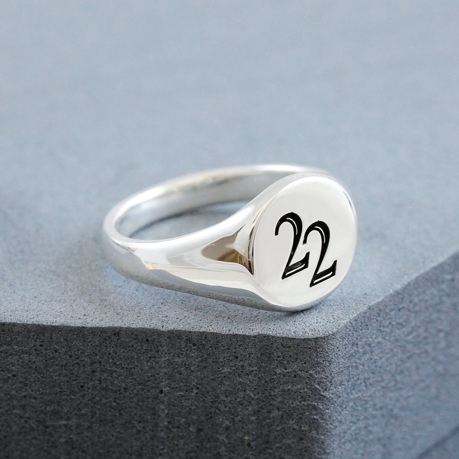 Silver ring with '22' engraving on a gray surface