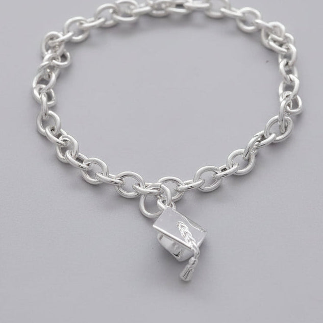 Silver chain bracelet with a graduation cap charm on a light blue background