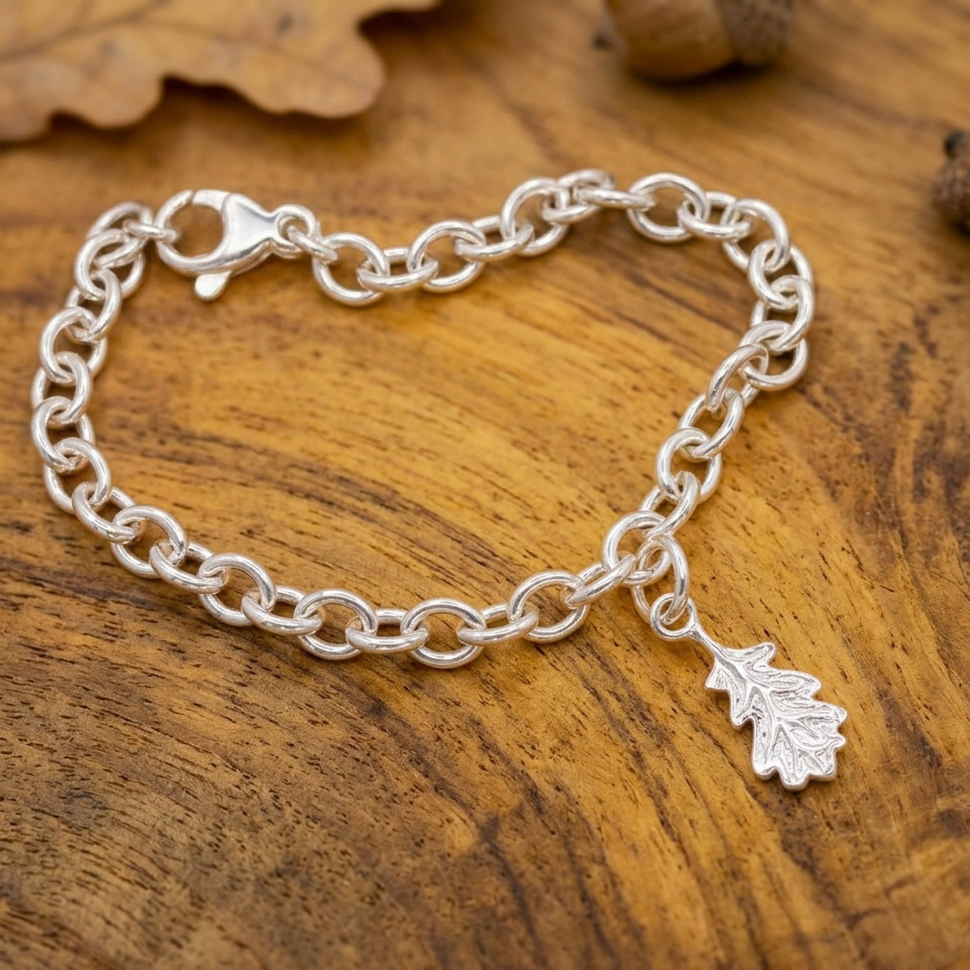 Silver chain bracelet with a leaf charm on a wooden surface
