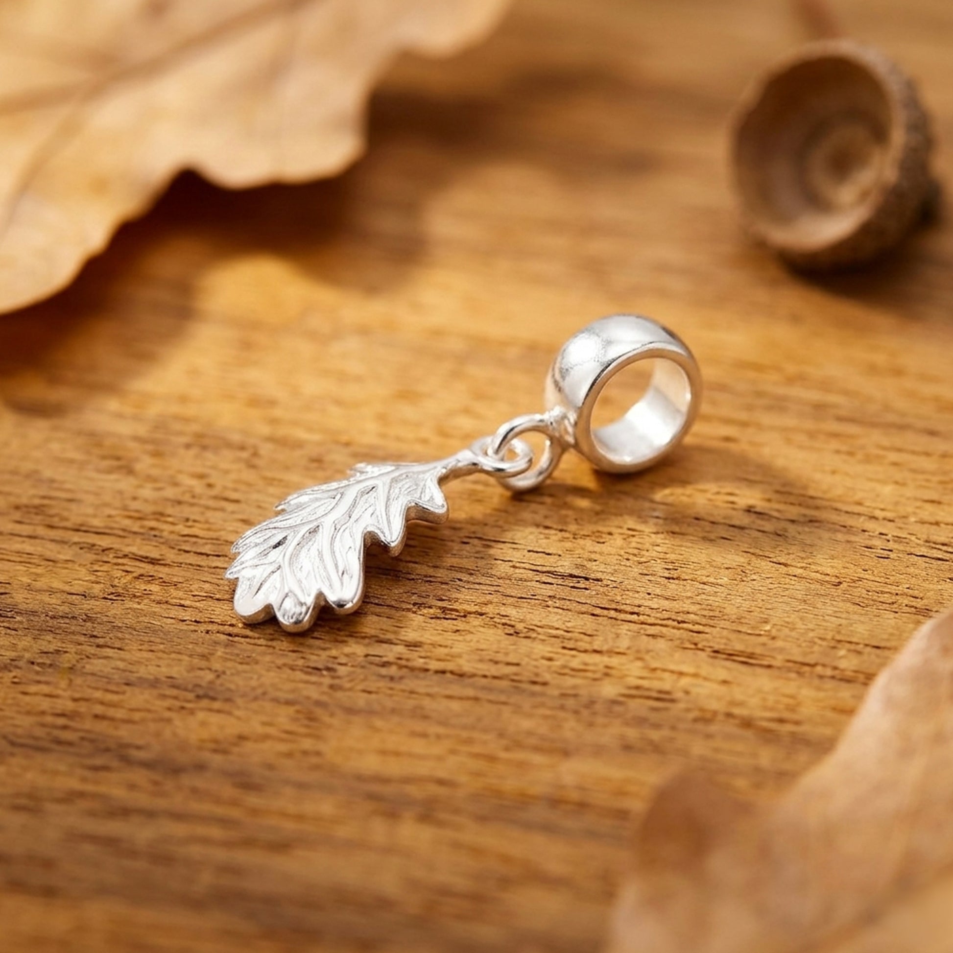 Silver leaf-shaped charm on a wooden surface