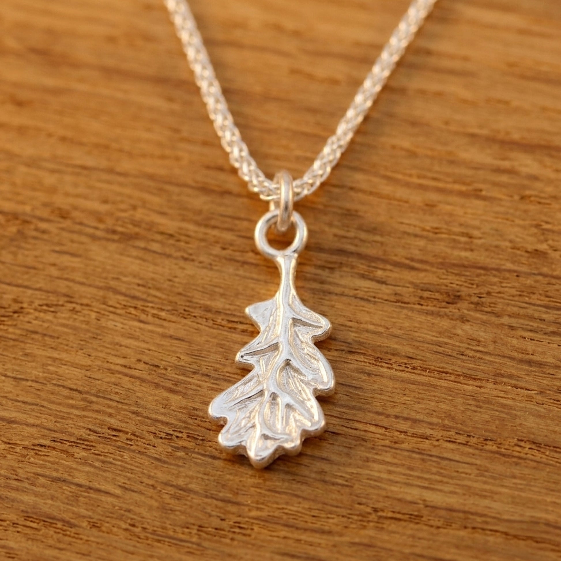 Silver leaf pendant necklace on a wooden surface