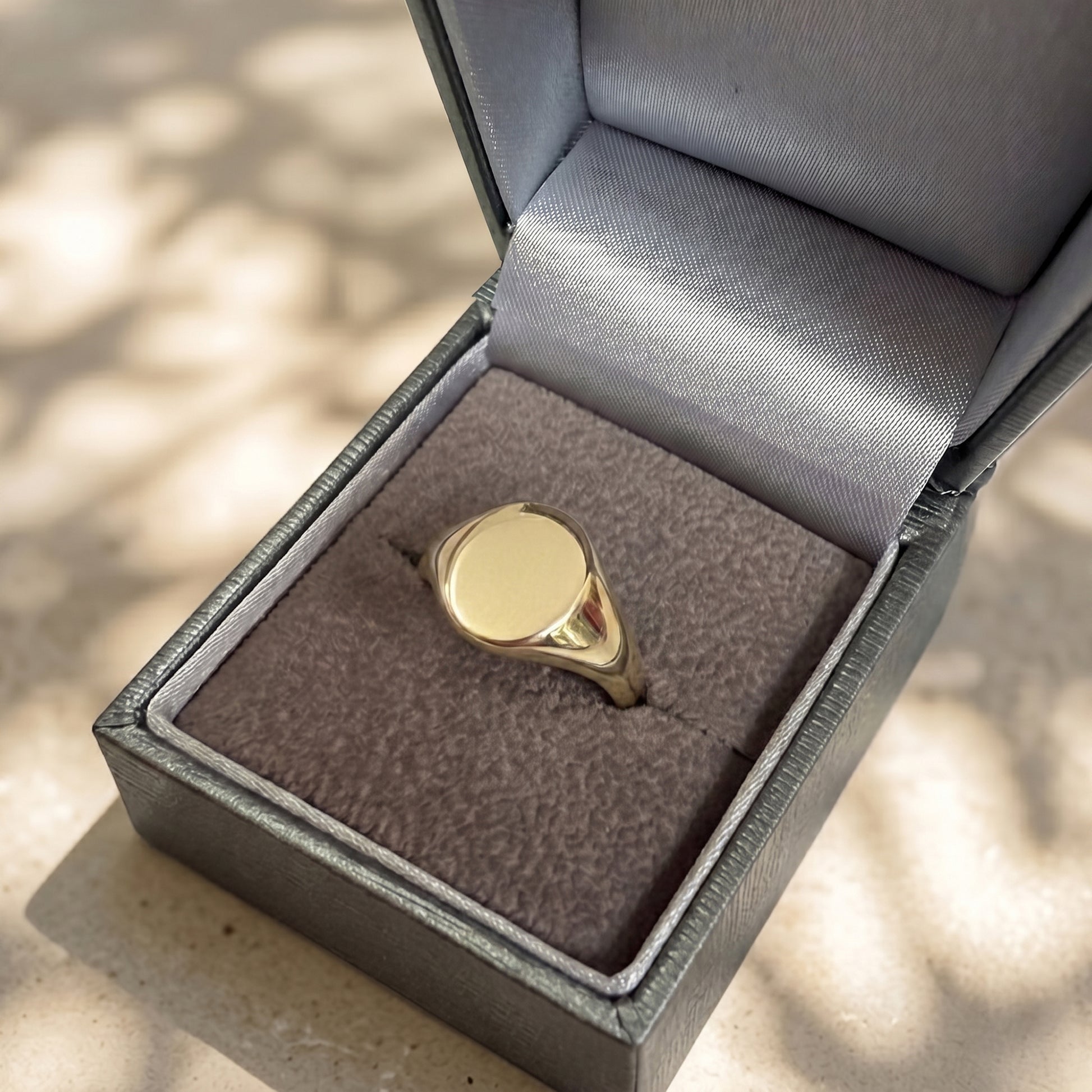 Gold ring in an open jewelry box on a textured surface