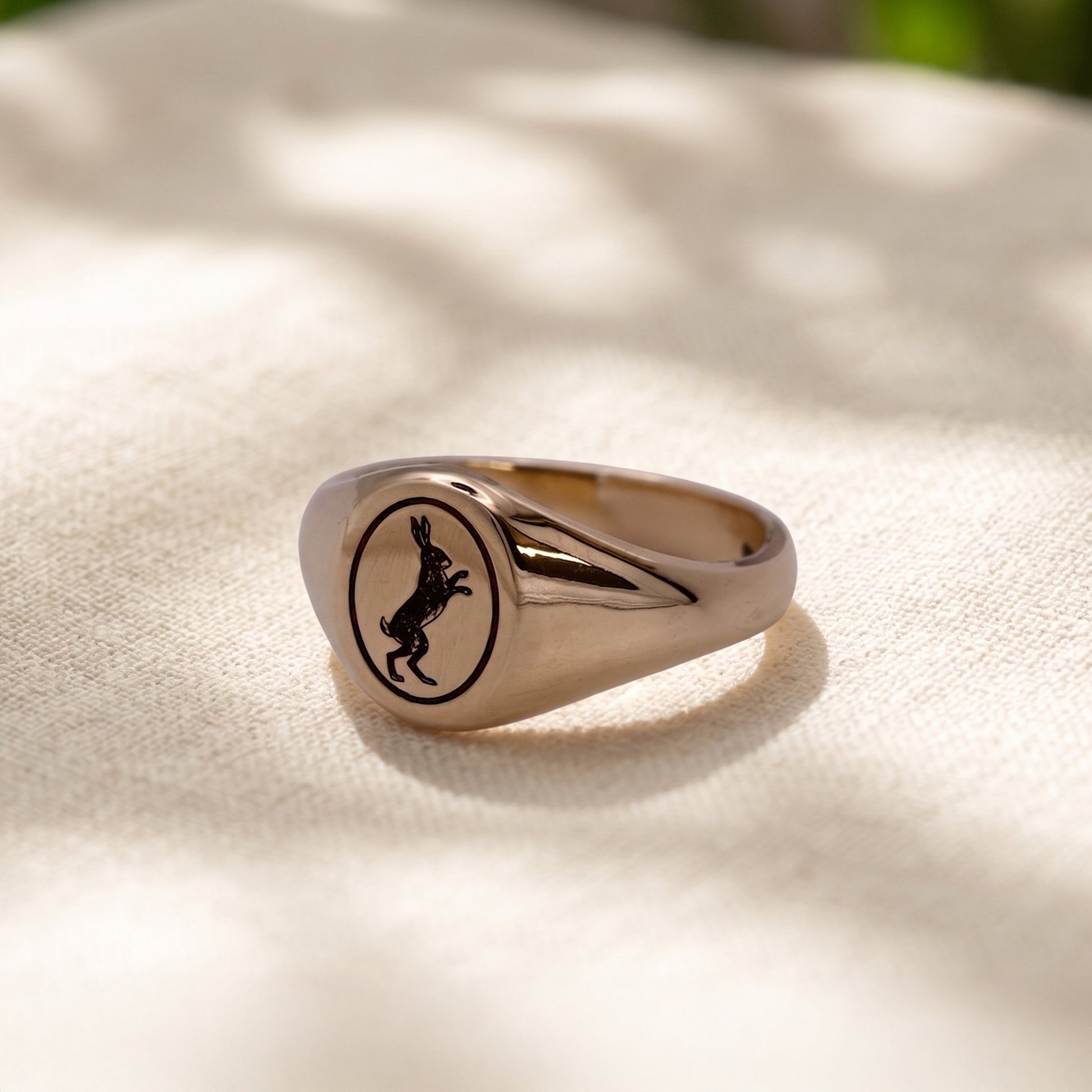 Silver ring with a black engraved design on a light fabric background