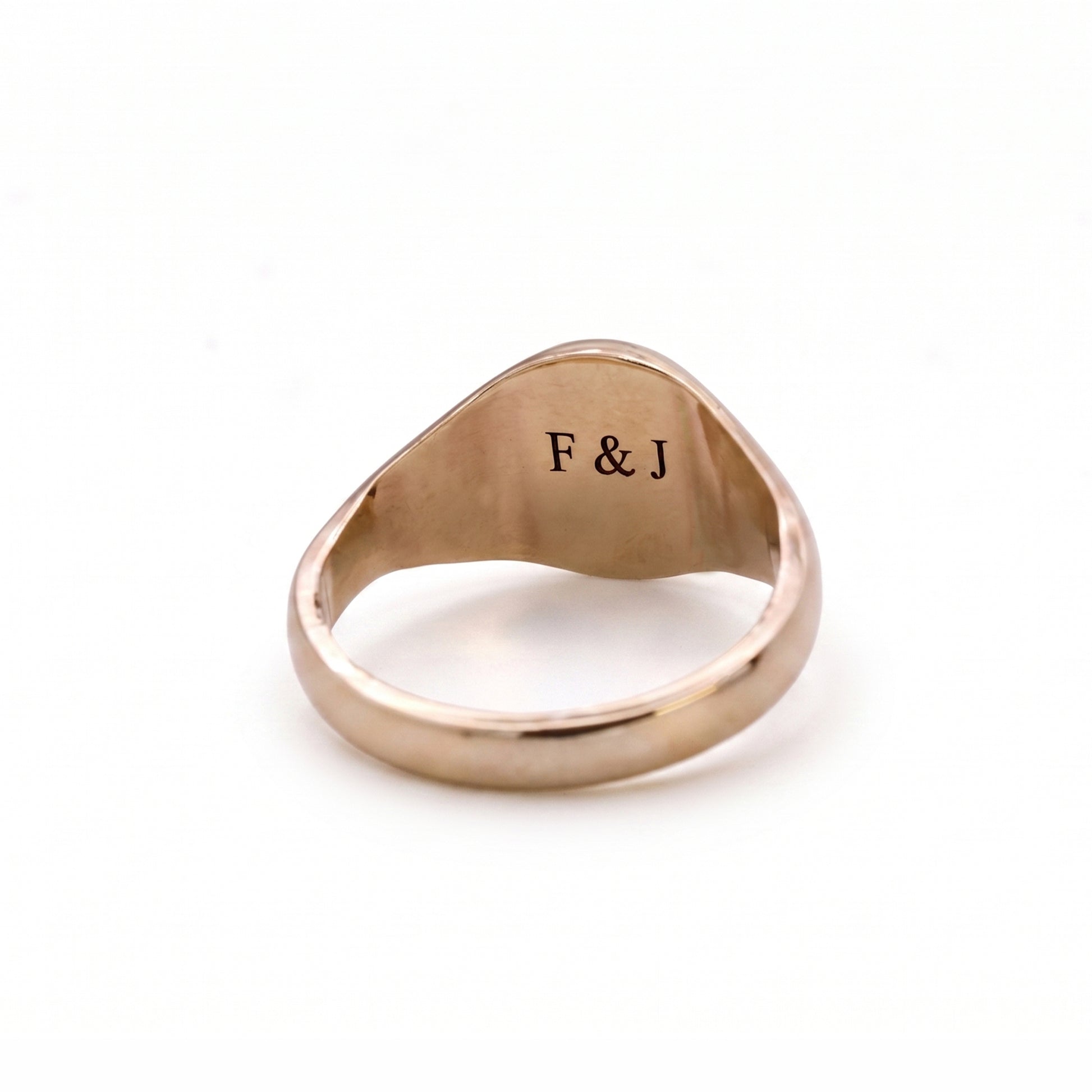 Rose gold ring with 'F & J' engraving on a white background