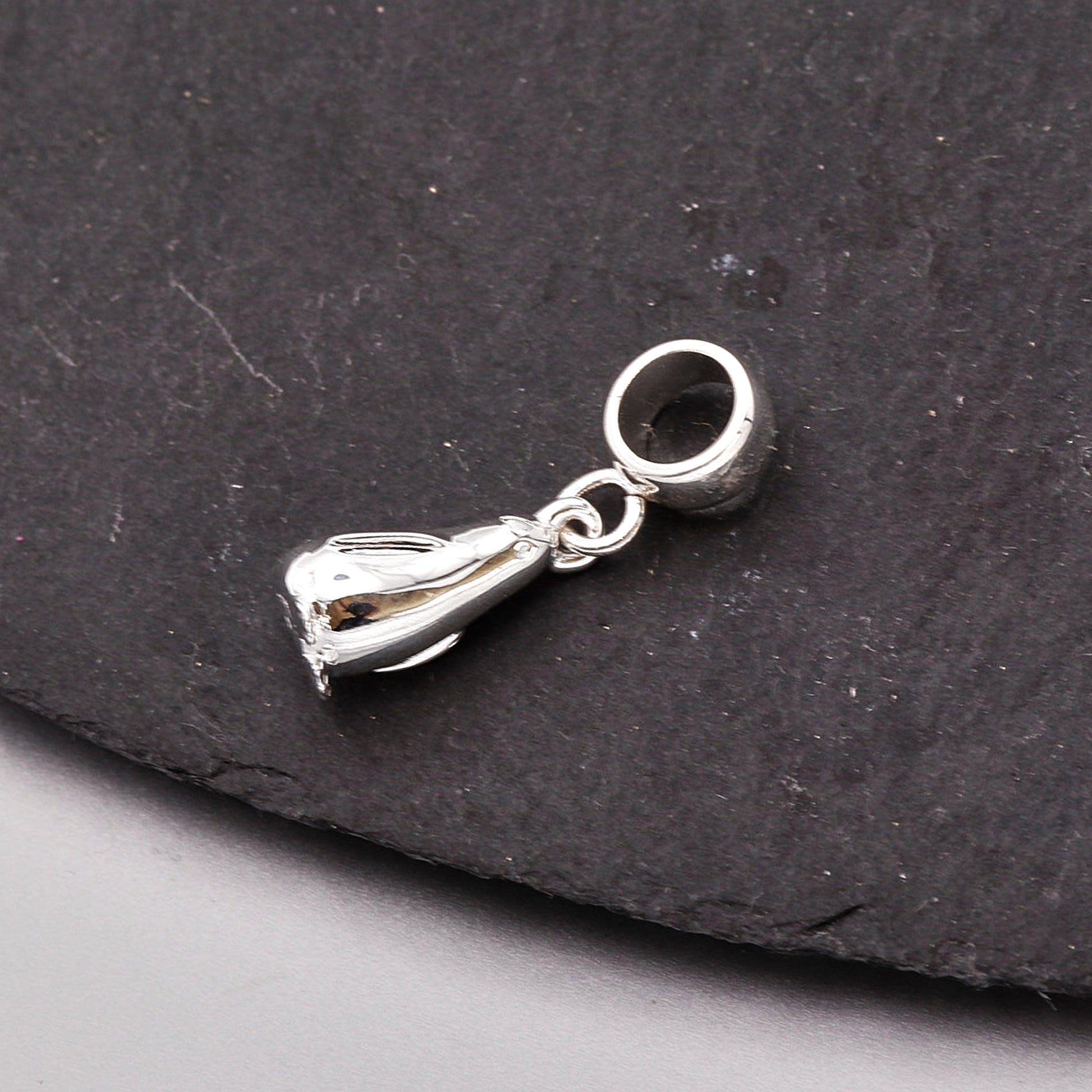 Silver penguin charm on a dark stone surface