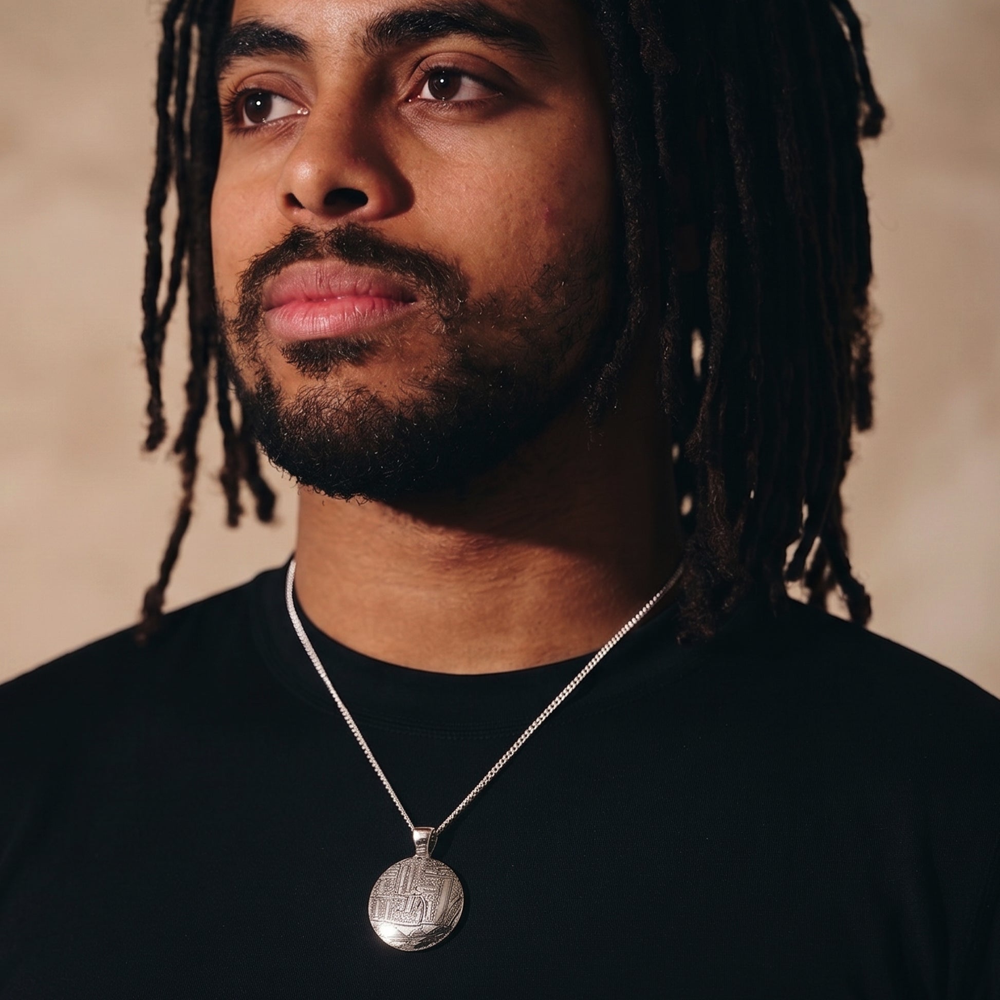 man in black t-shirt wearing abstract silver necklace
