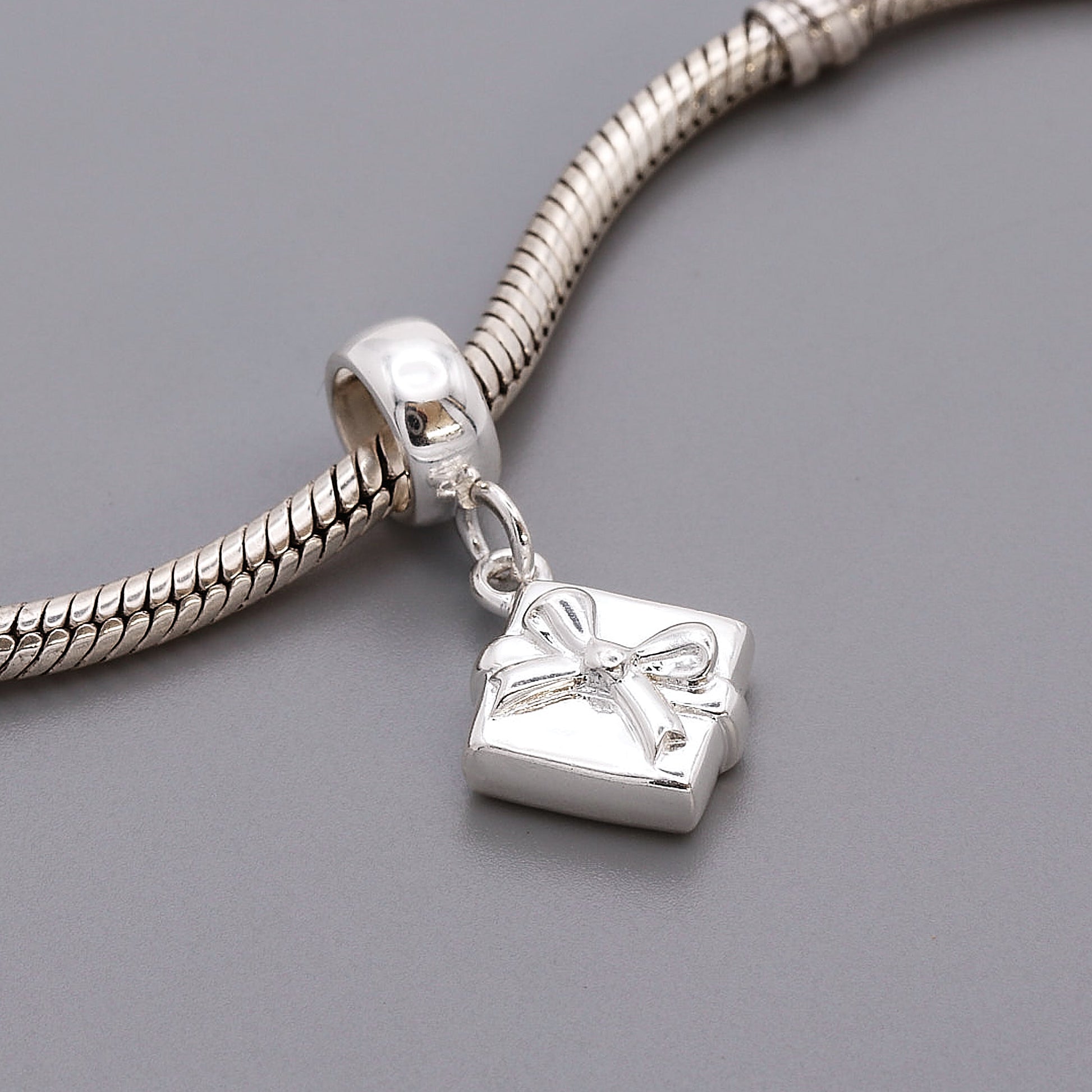 silver present with bow charm shown on charm carrier & bead bracelet