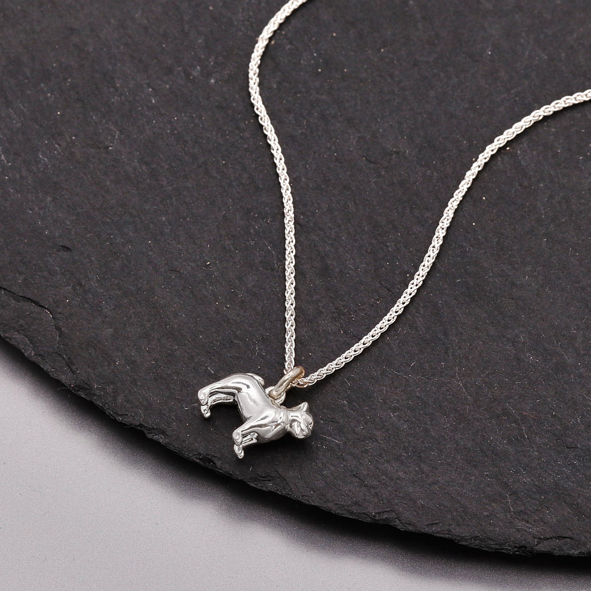 Silver pug dog pendant necklace on a dark stone surface