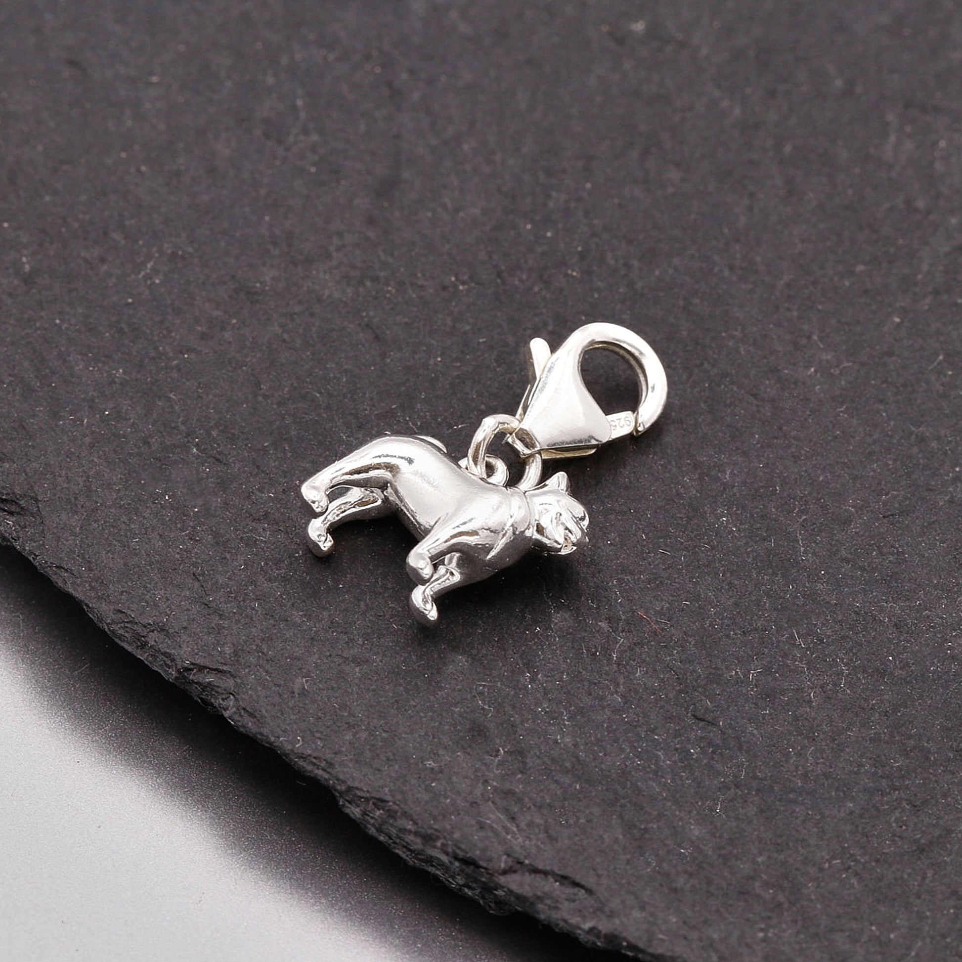 Silver pug dog charm on a black stone background
