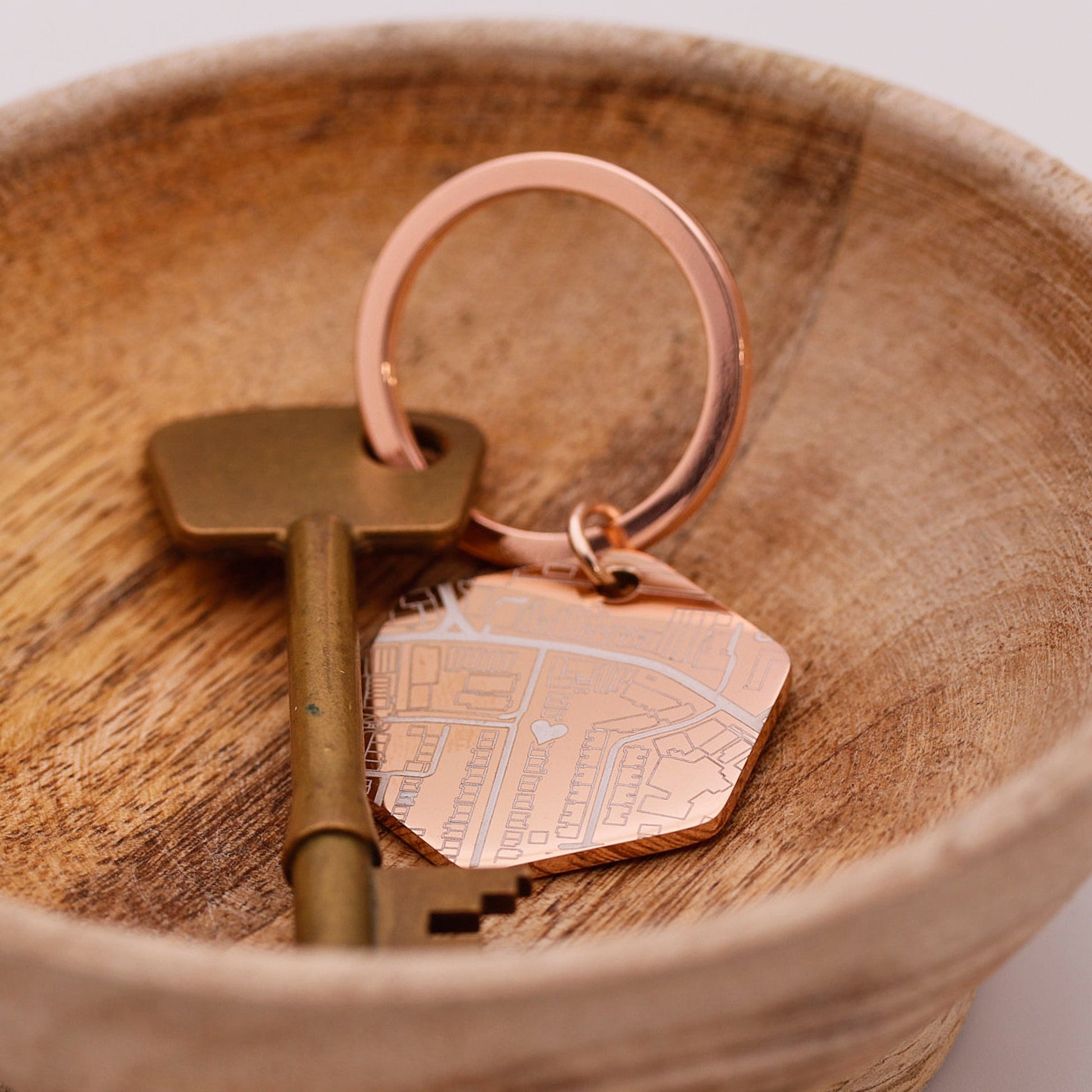 Keychain with a street map design and brass key on a wooden surface