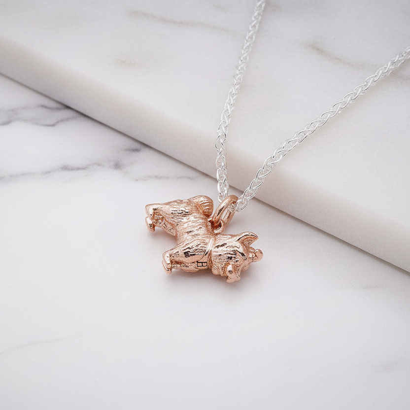 Rose gold yorkshire terrier pendant with a chain on a marble surface