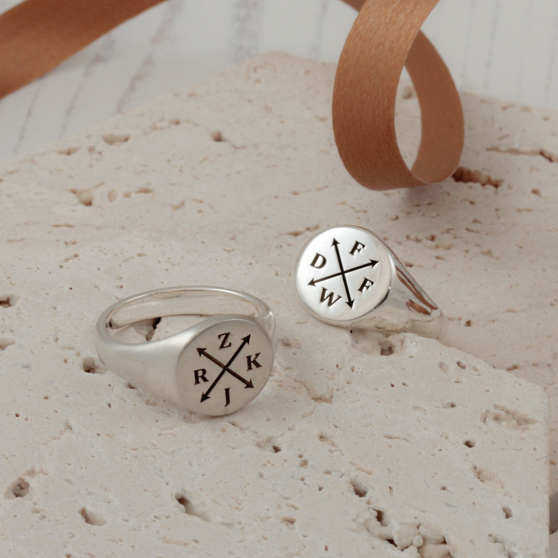 silver signet rings engraved with initials on a white background