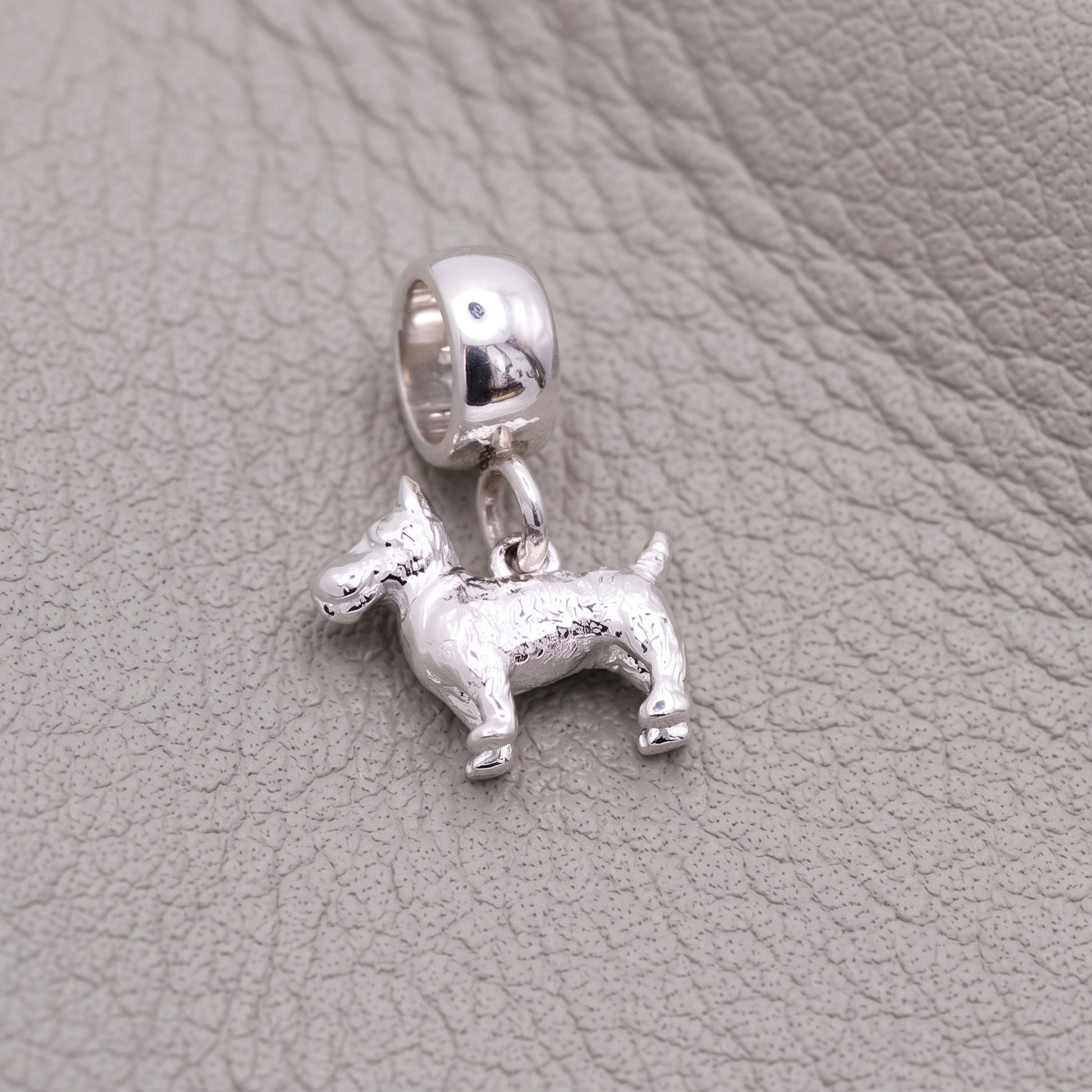 Silver dog-shaped pendant on a textured gray surface