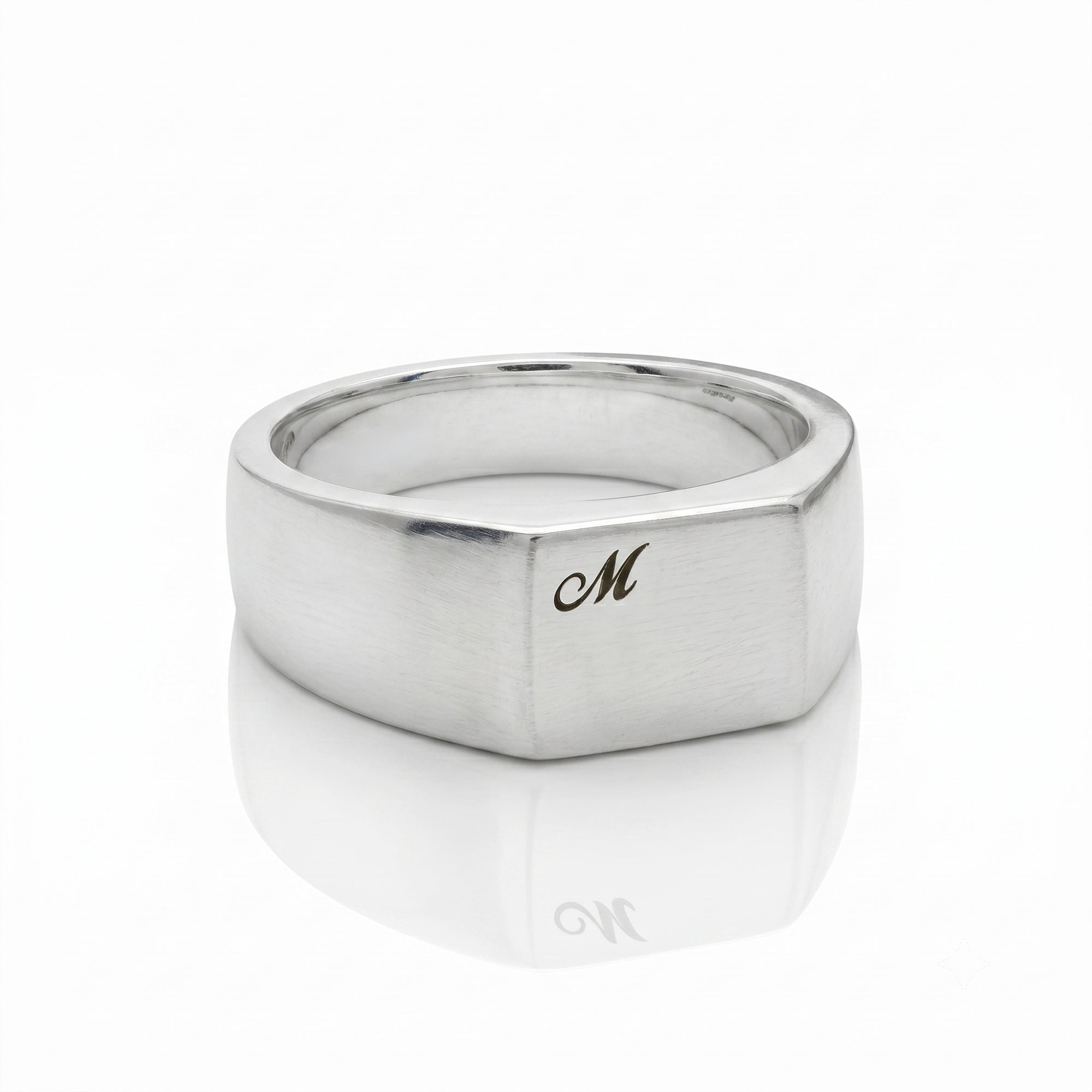 Silver ring with a gold 'M' on a white background