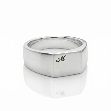 Silver ring with a gold 'M' on a white background