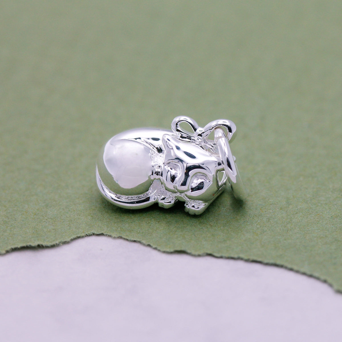 Close-up of sterling silver cat charm with tiny bow collar detail