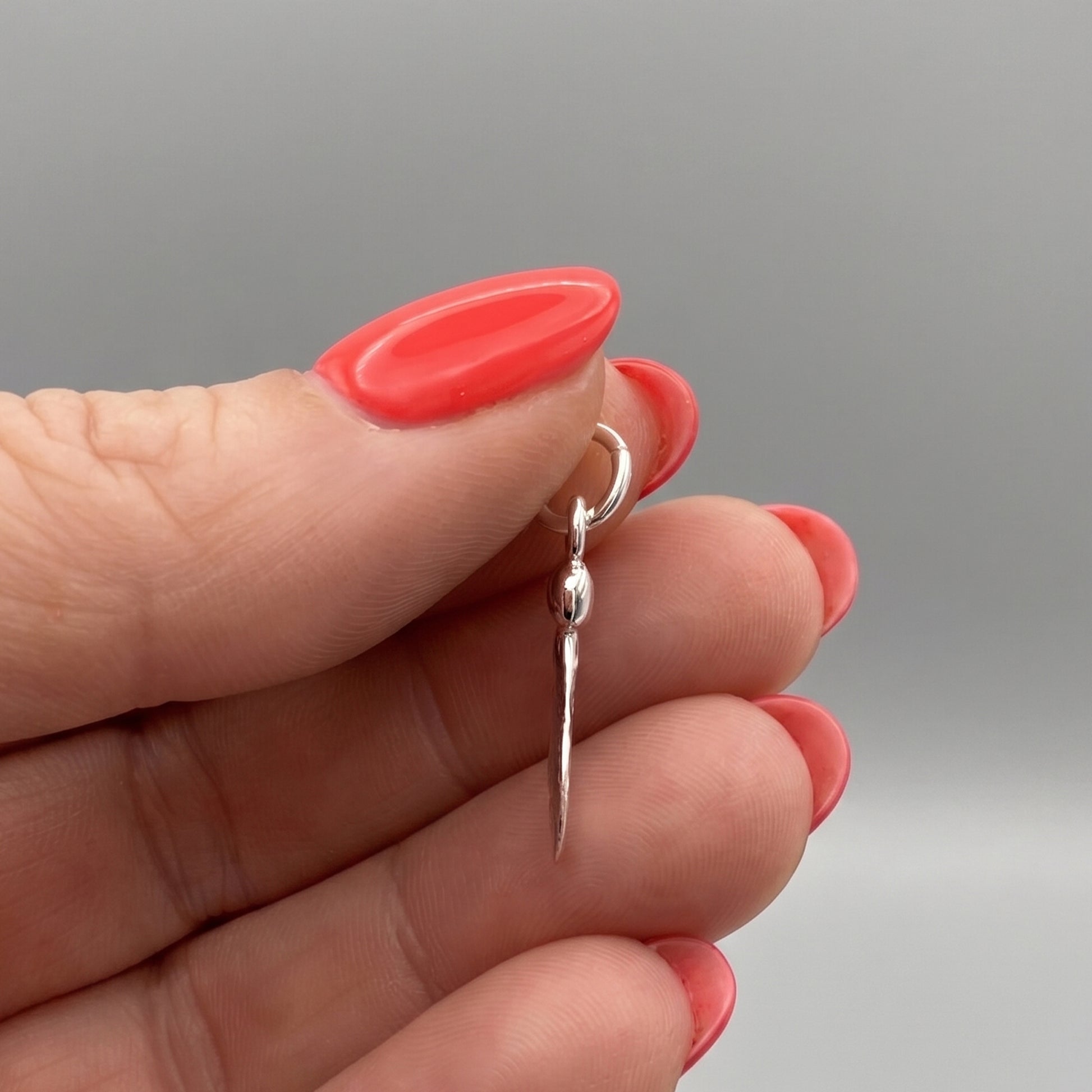 Silver seed-shaped pendant charm in a womans hands