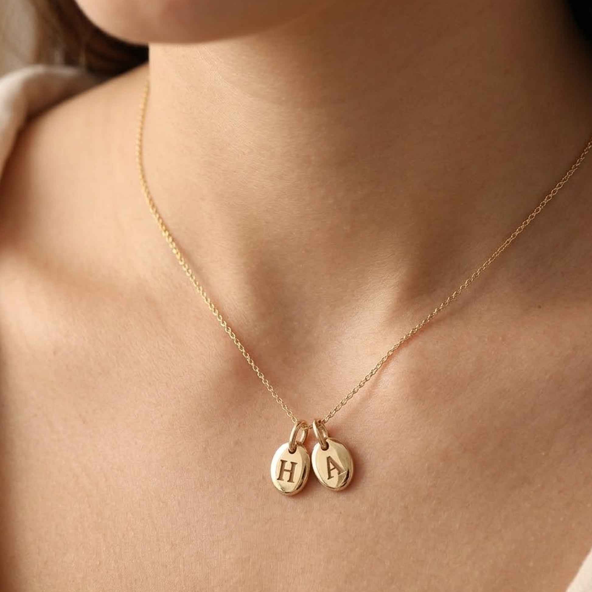two gold engraved pendants on one chain around a womans neck