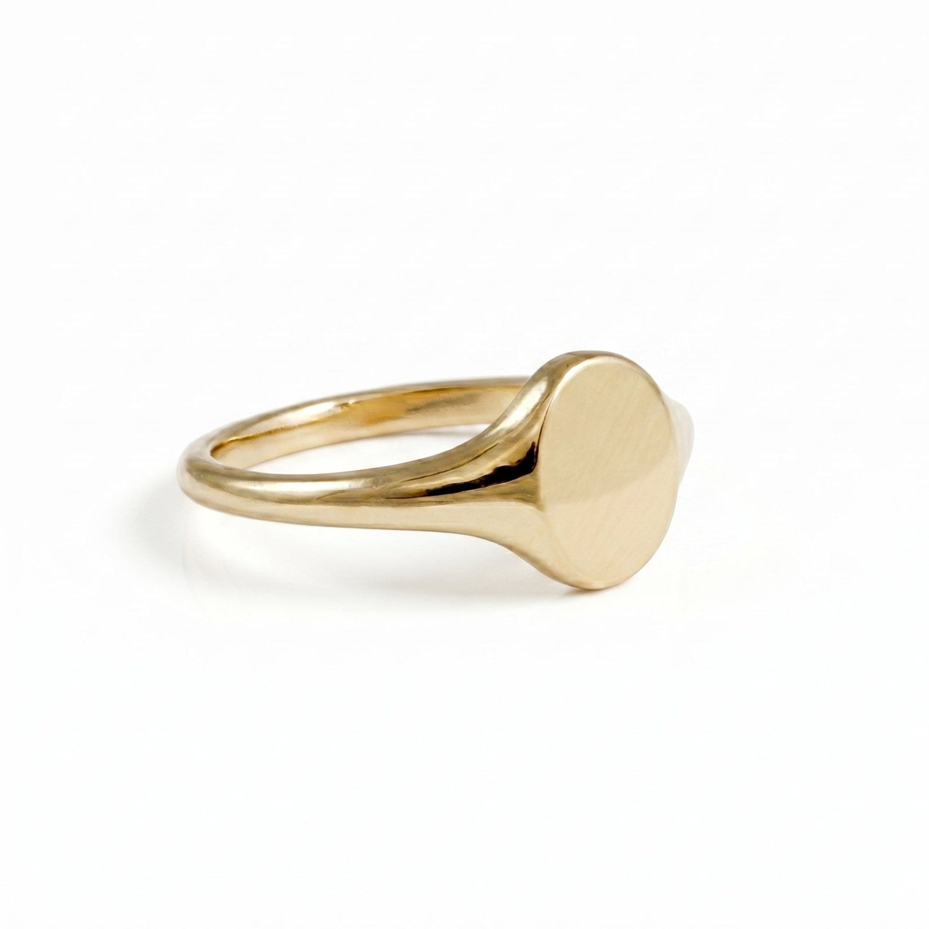 solid gold oval signet ring on white background