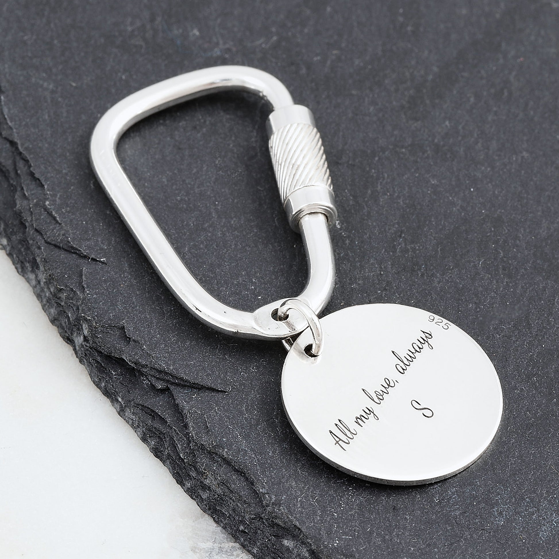Silver keychain with engraved message on a dark surface