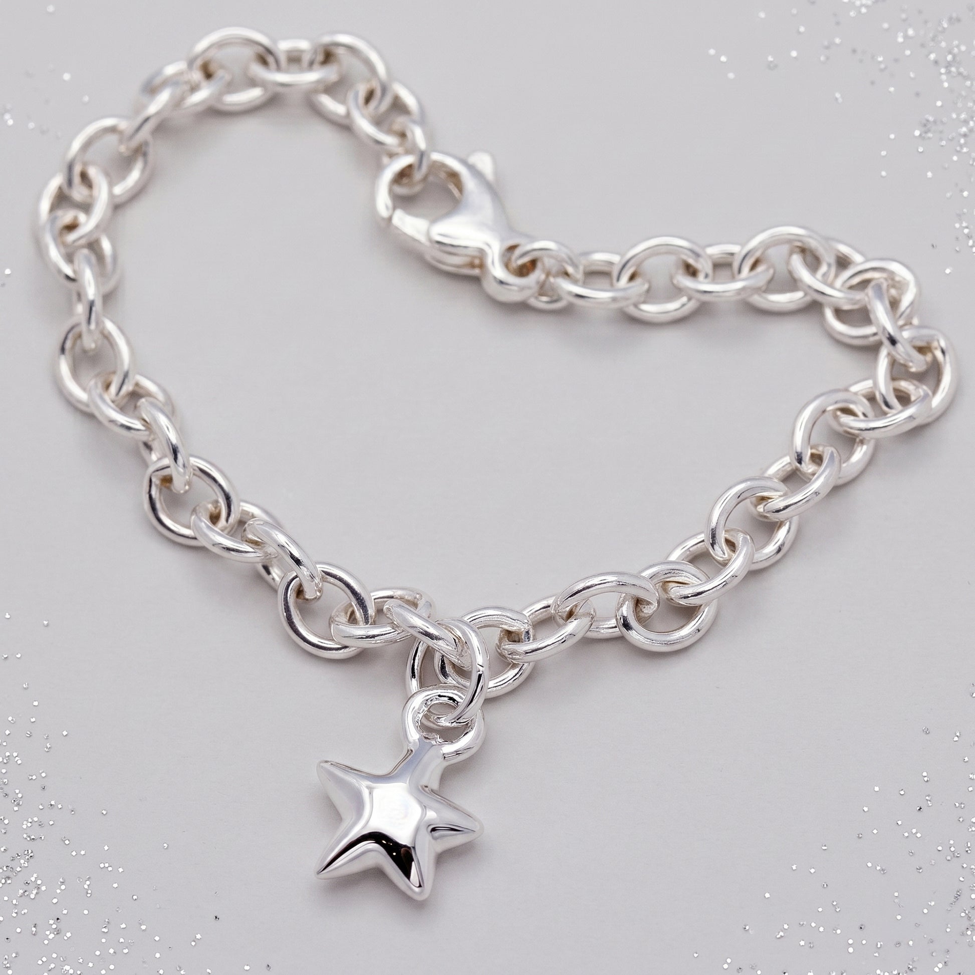 Silver chain bracelet with a star charm on a light gray background