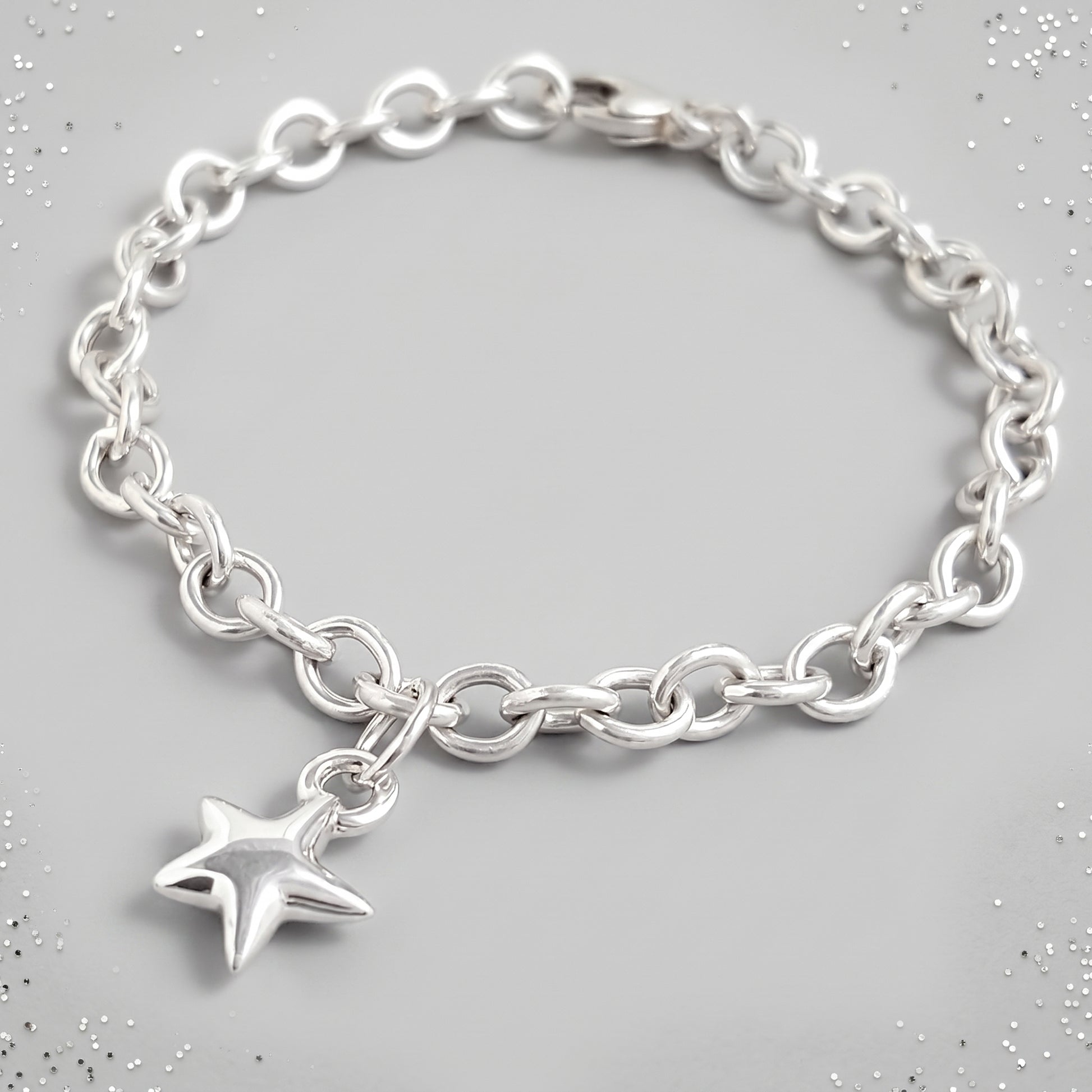 silver star charm bracelet on grey background